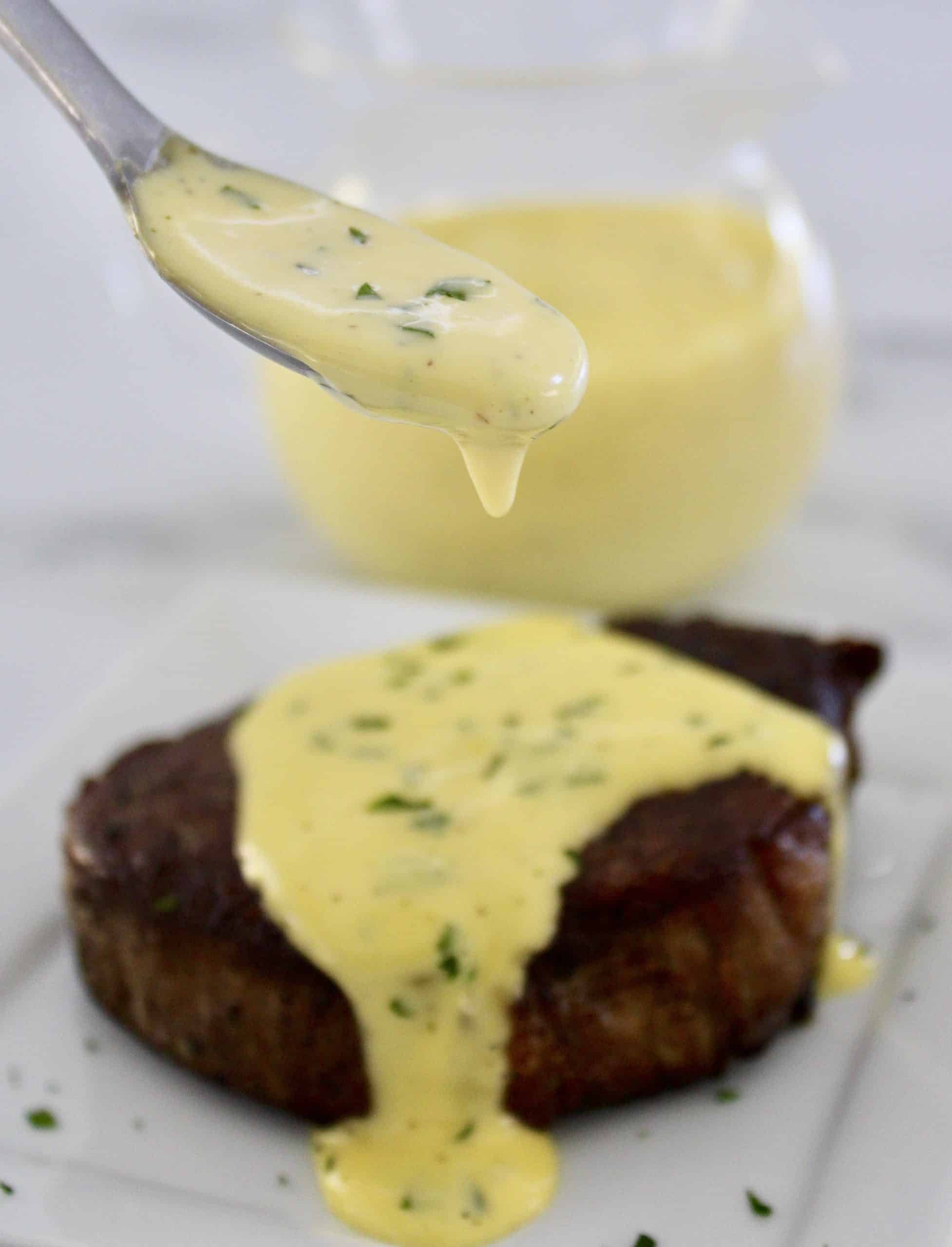 Béarnaise Sauce being spooned over filet mignon on white plate