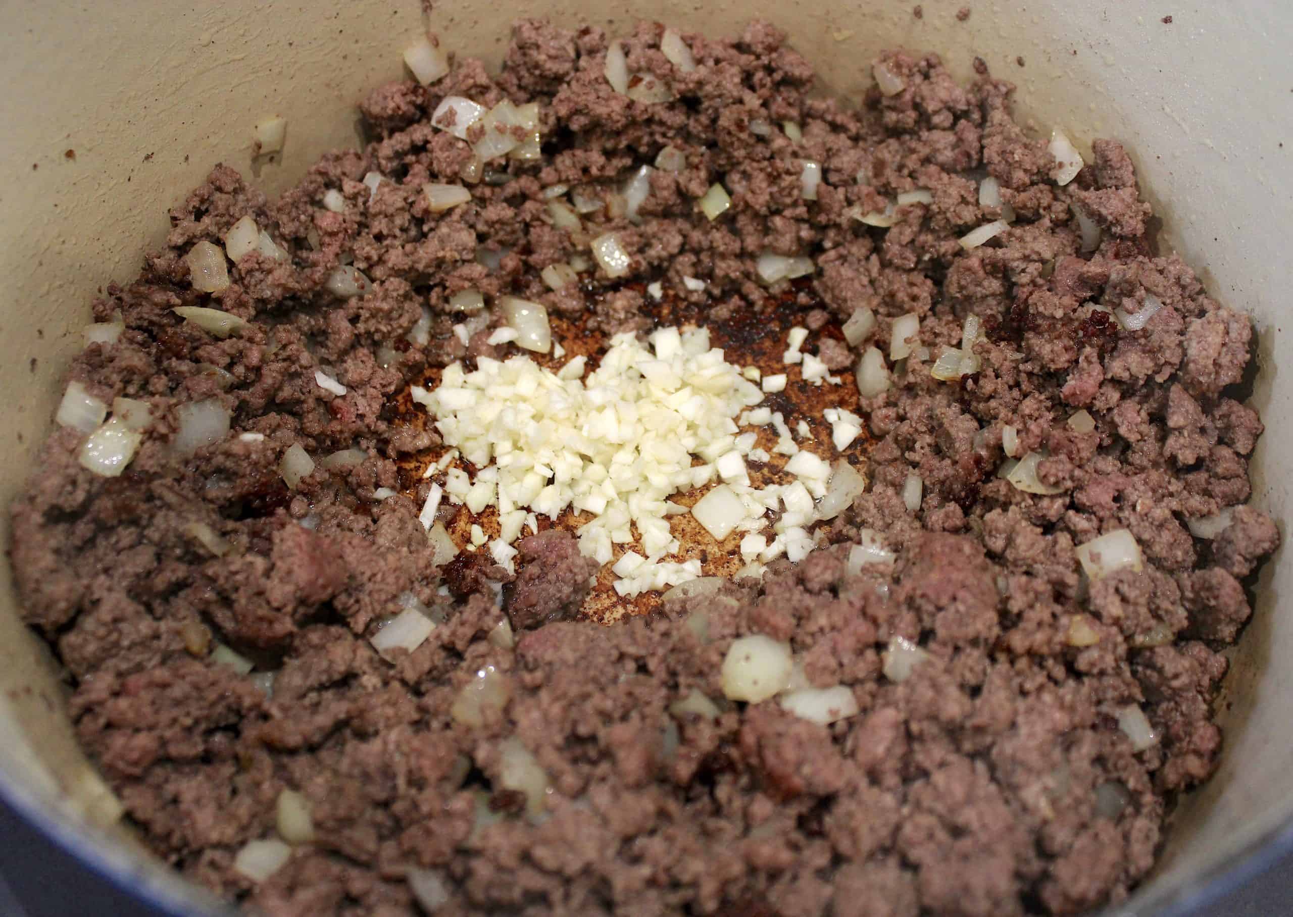 cooked ground beef and onions in pot with minced garlic in the center