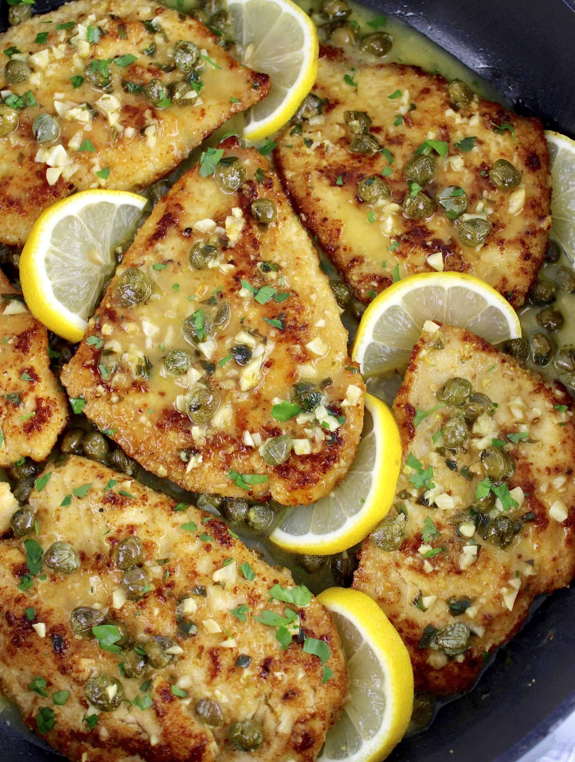 Chicken Piccata in skillet with lemon slices with chopped parsley