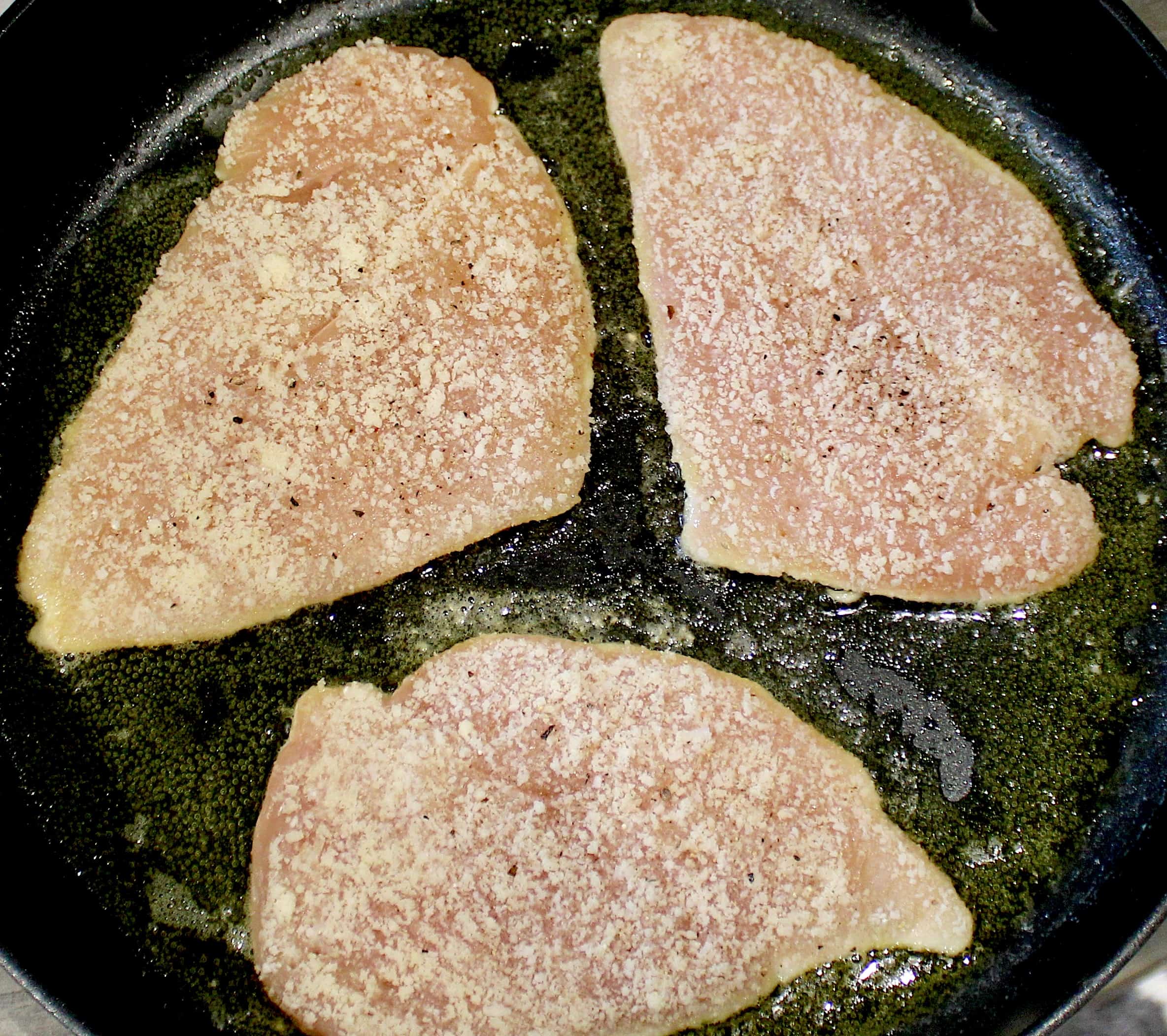 3 chicken breasts being cooked in skillet
