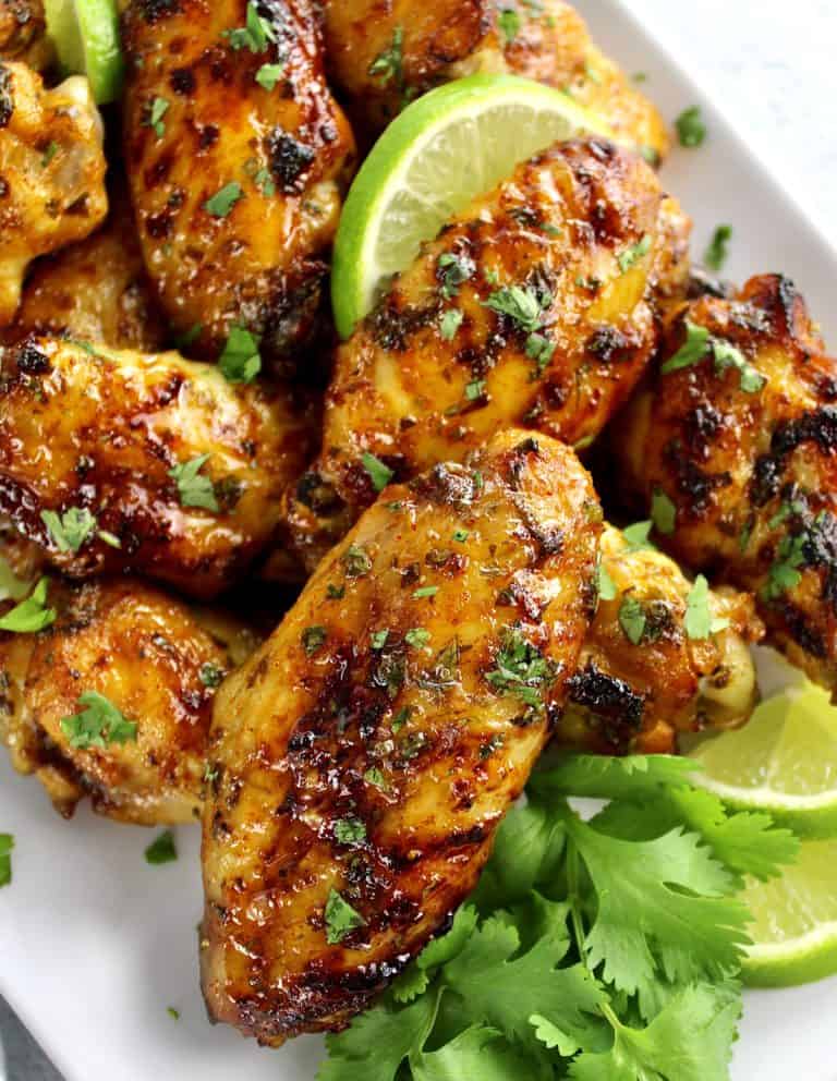 Cilantro Lime Chicken Wings on white plate with cilantro garnish and slices of lime