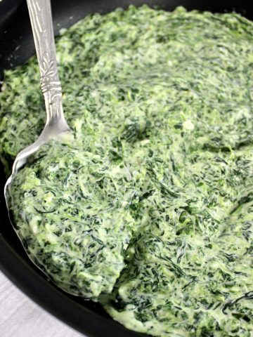 creamed spinach in skillet with silver ladle