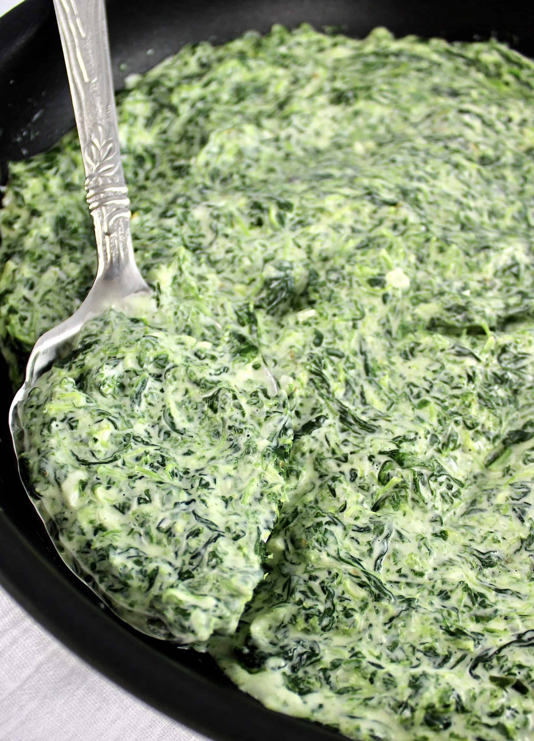 creamed spinach in skillet with silver ladle