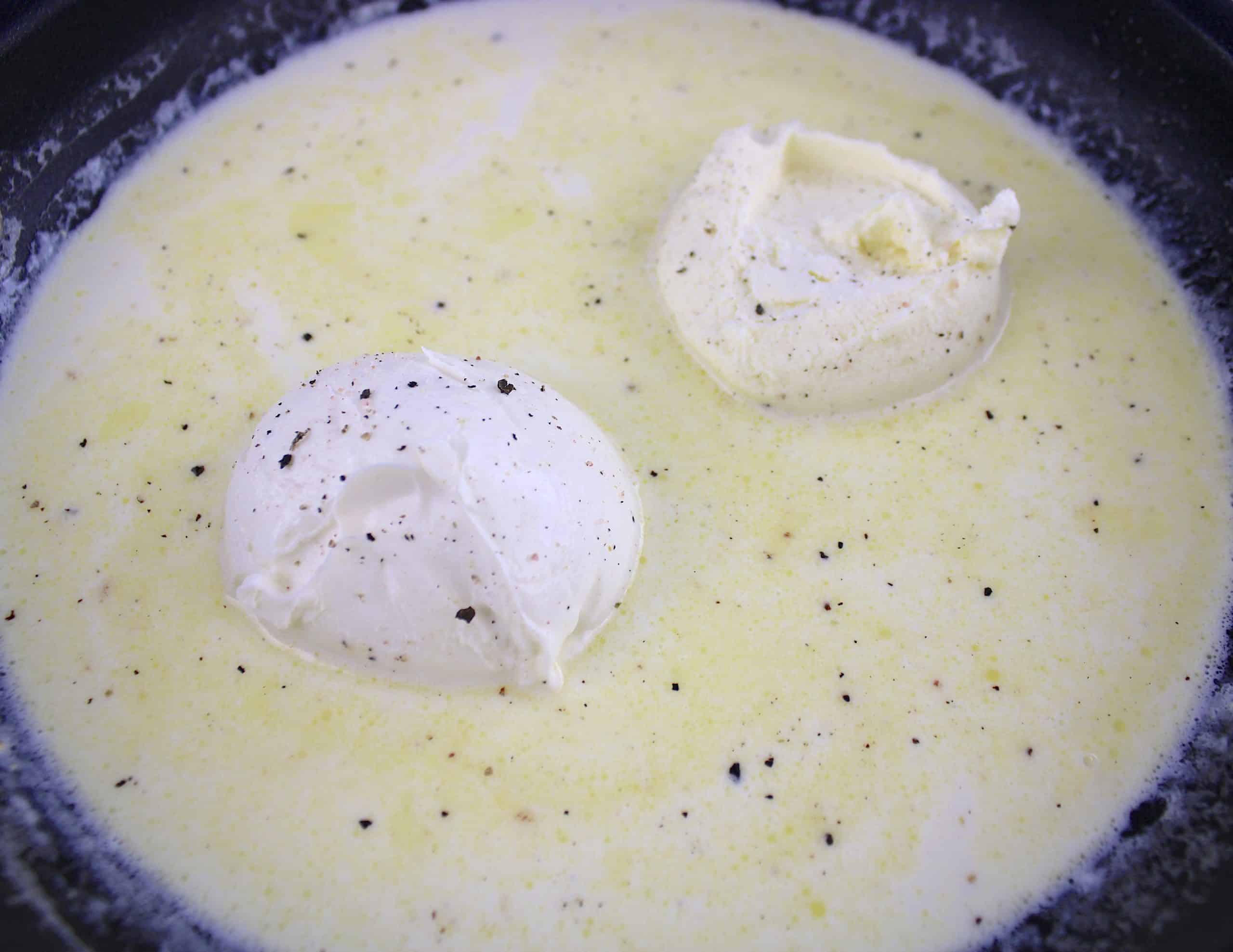 cream cheese clumps in heavy cream with salt and pepper in skillet