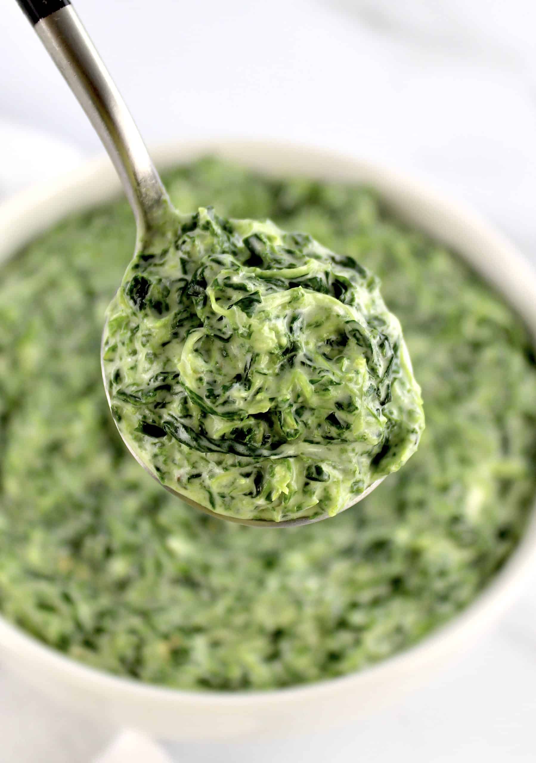spoonful of creamed spinach held up over bowl
