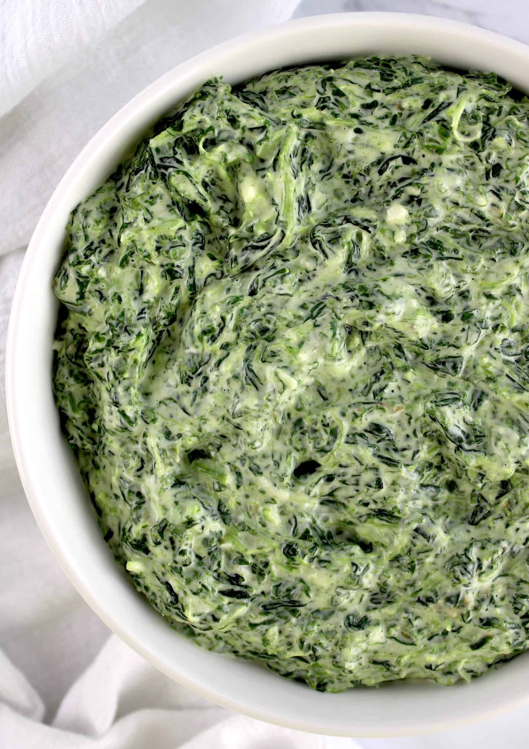 overhead view of creamed spinach in white bowl