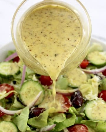 Homemade Italian Dressing being poured over salad from glass