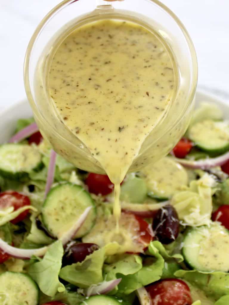 Homemade Italian Dressing being poured over salad from glass