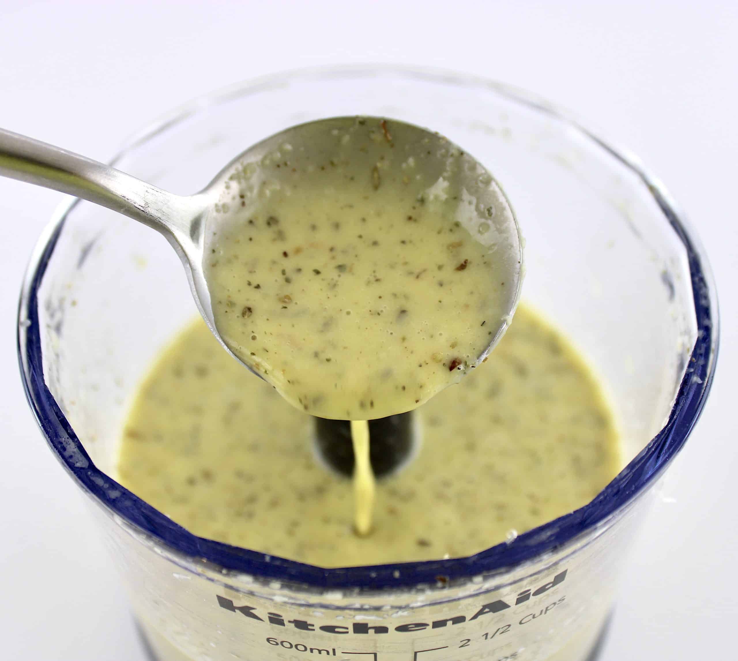 Homemade Italian Dressing being spooned into mini chopper bowl