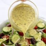 Homemade Italian Dressing being poured over salad from glass