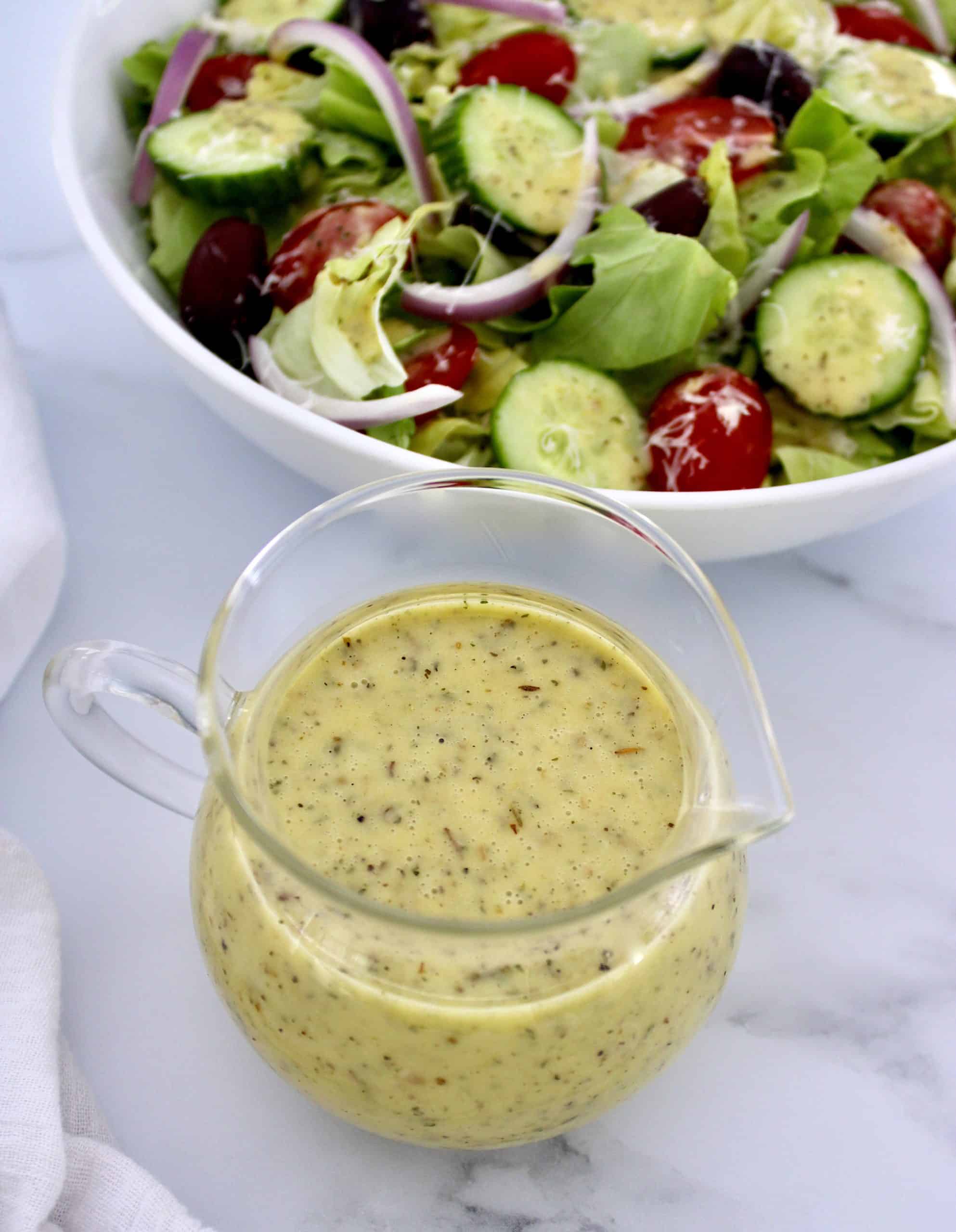 Homemade Italian Dressing in glass container with salad in background