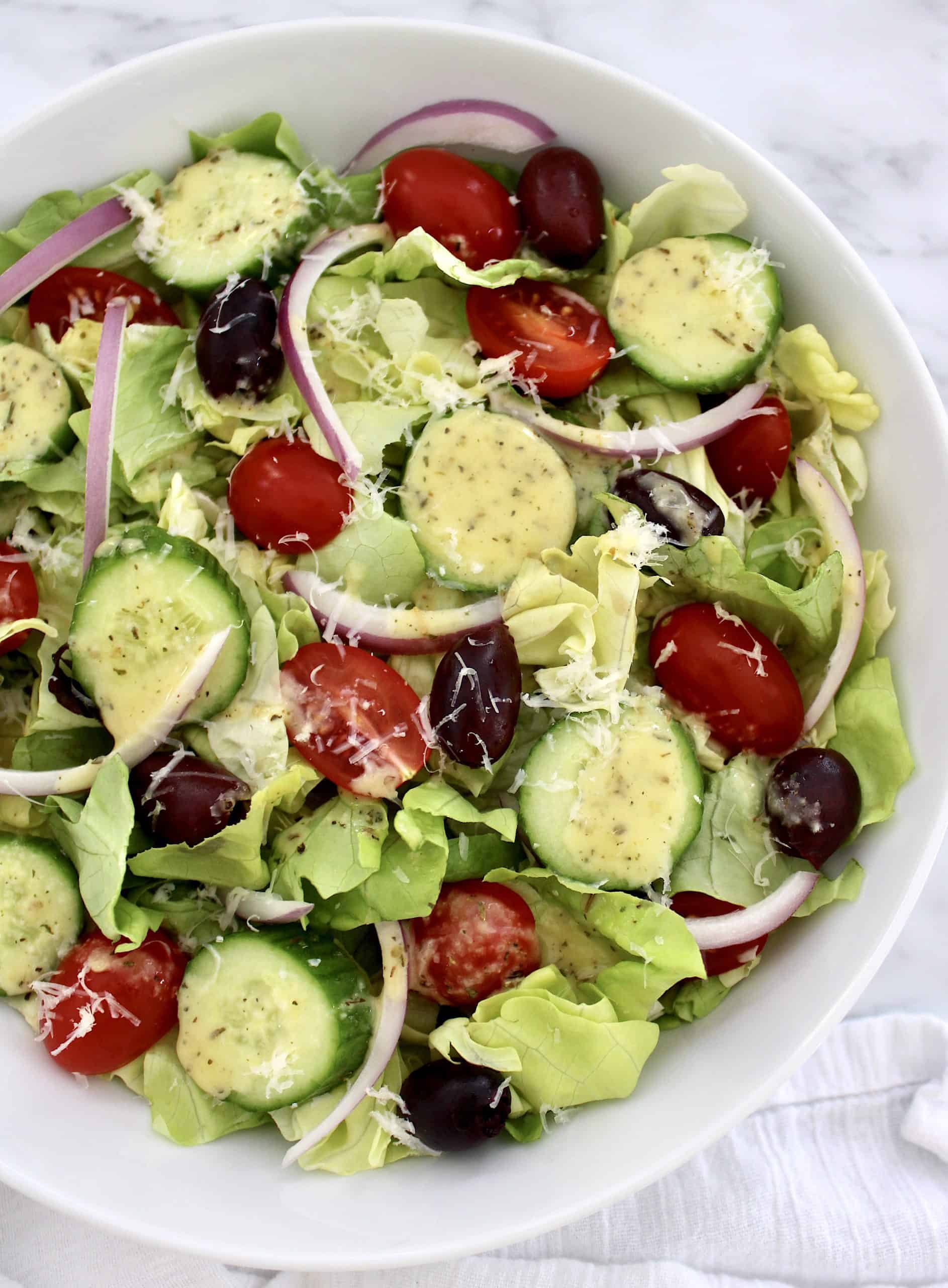 overhead view of salad with sliced onions tomatoes cucumbers and olives