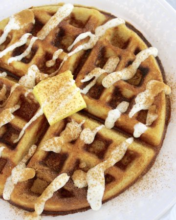 overhead view of Keto Cinnamon Roll Waffles with icing and pad of butter on top