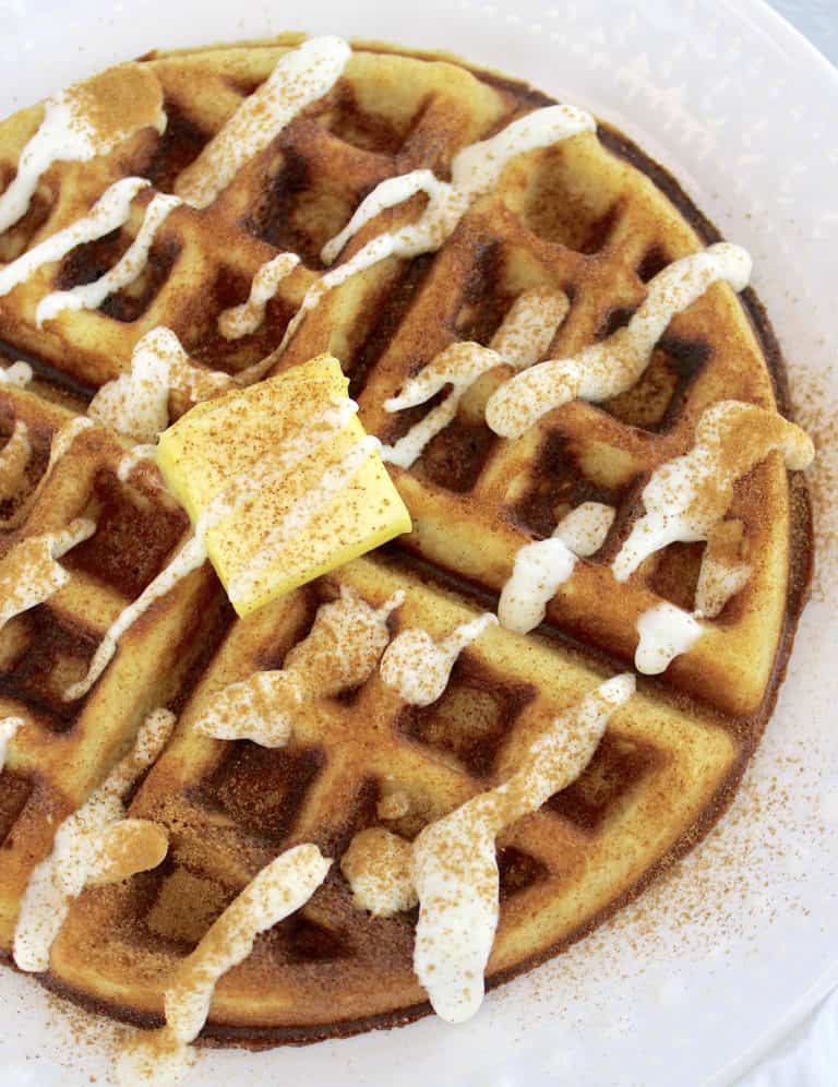 overhead view of Keto Cinnamon Roll Waffles with icing and pad of butter on top