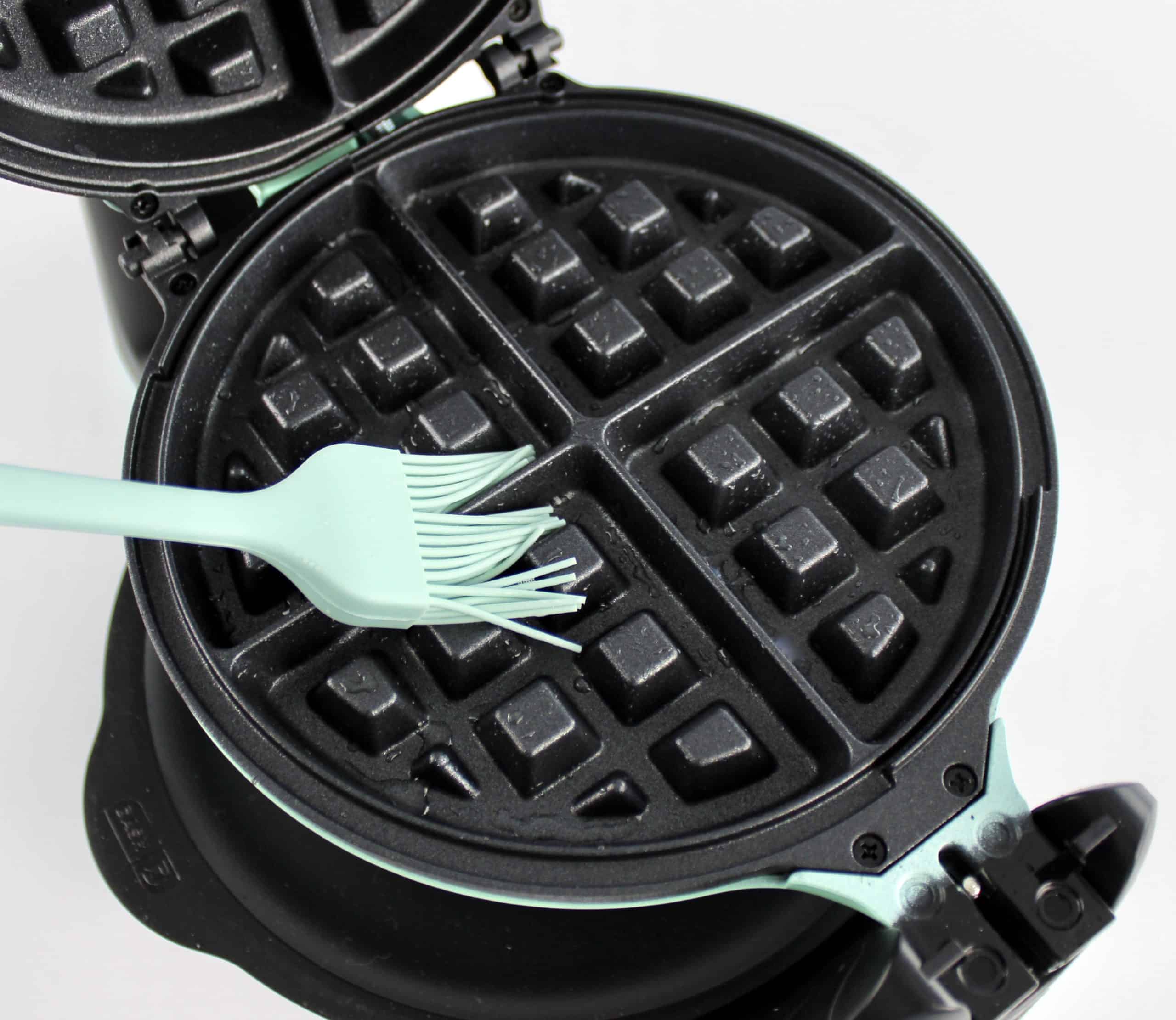 waffle plates being brushed with blue silicone brush with oil