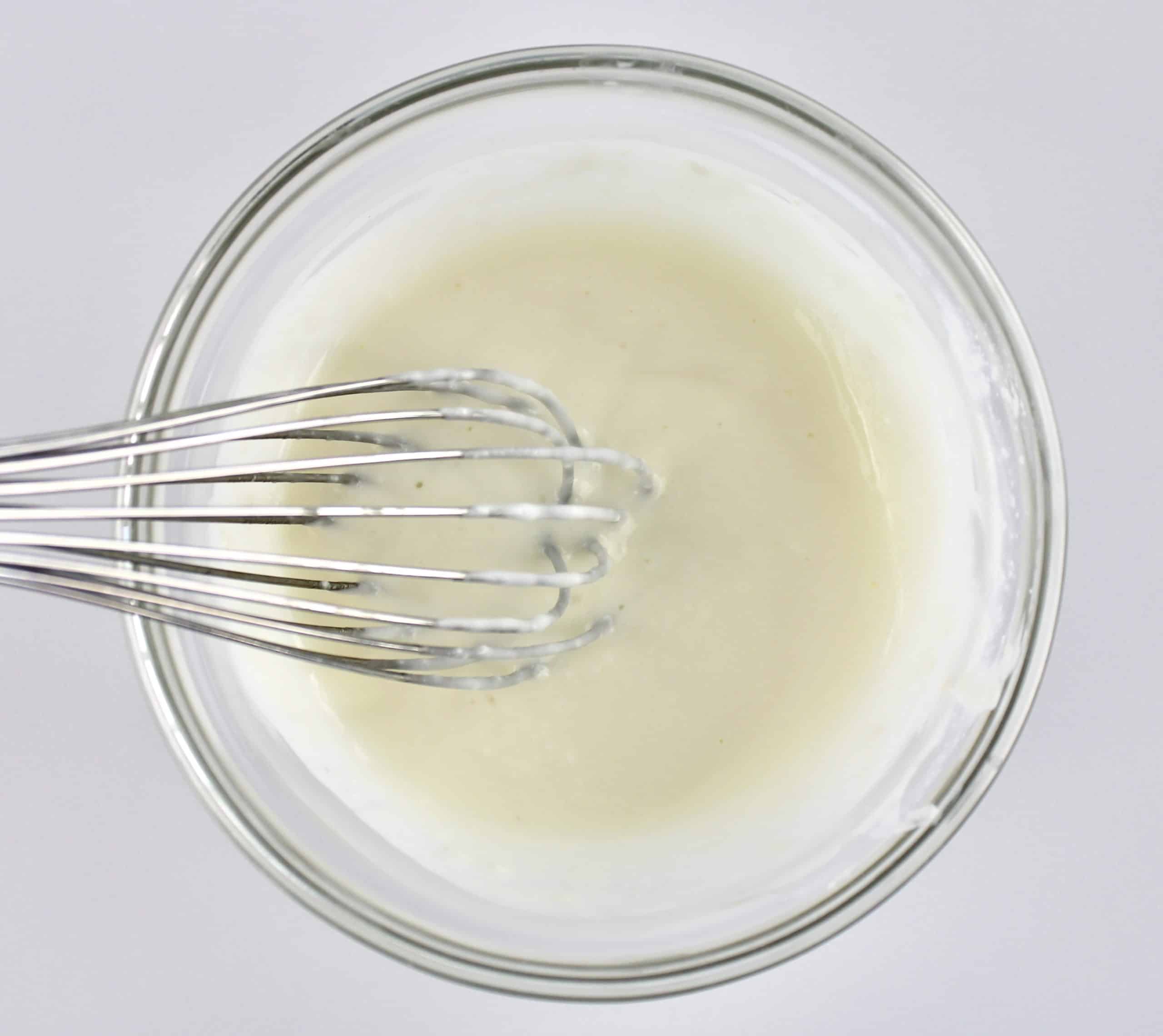 cream cheese icing in glass bowl with whisk
