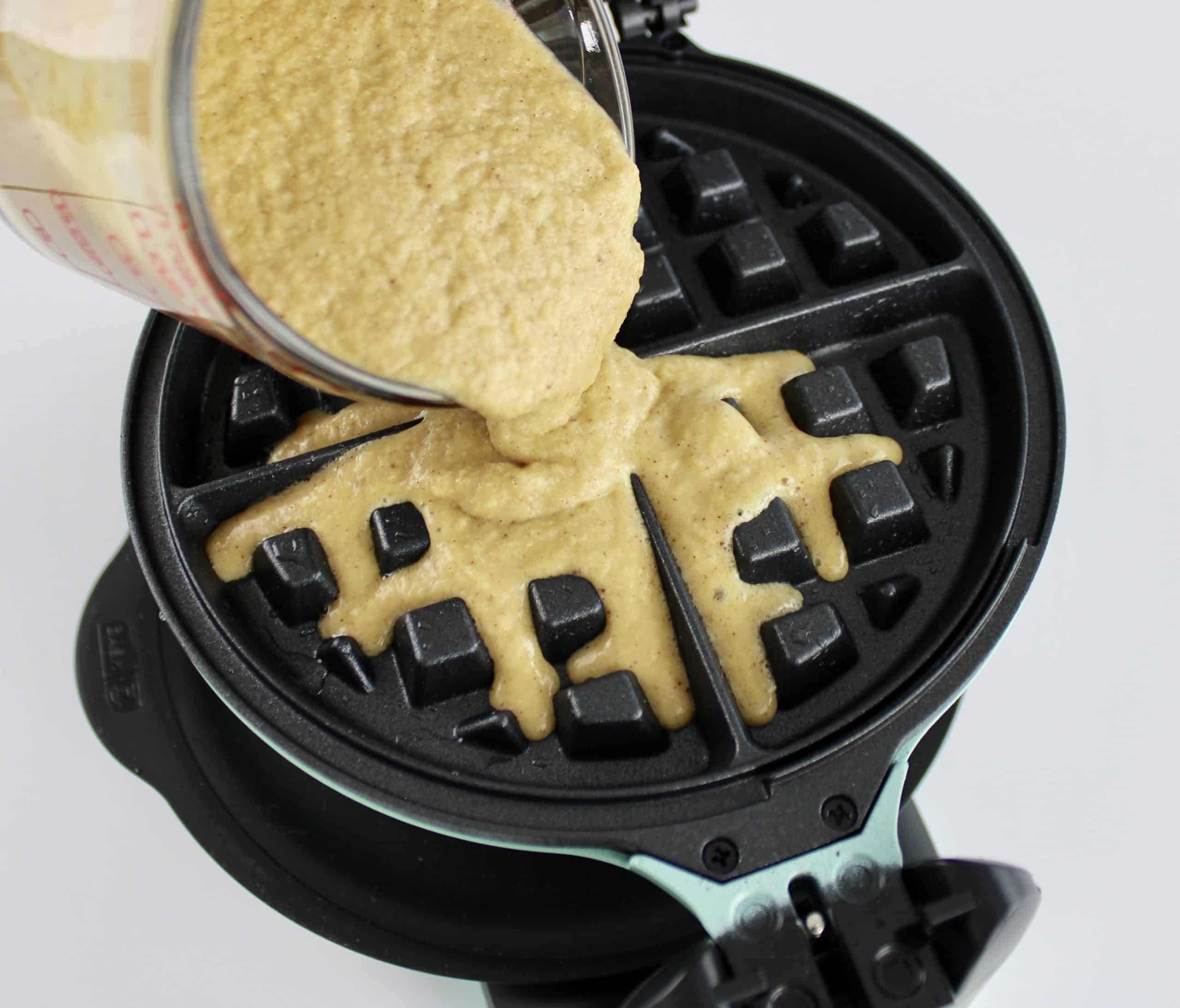 cinnamon roll waffle batter being poured into waffle maker