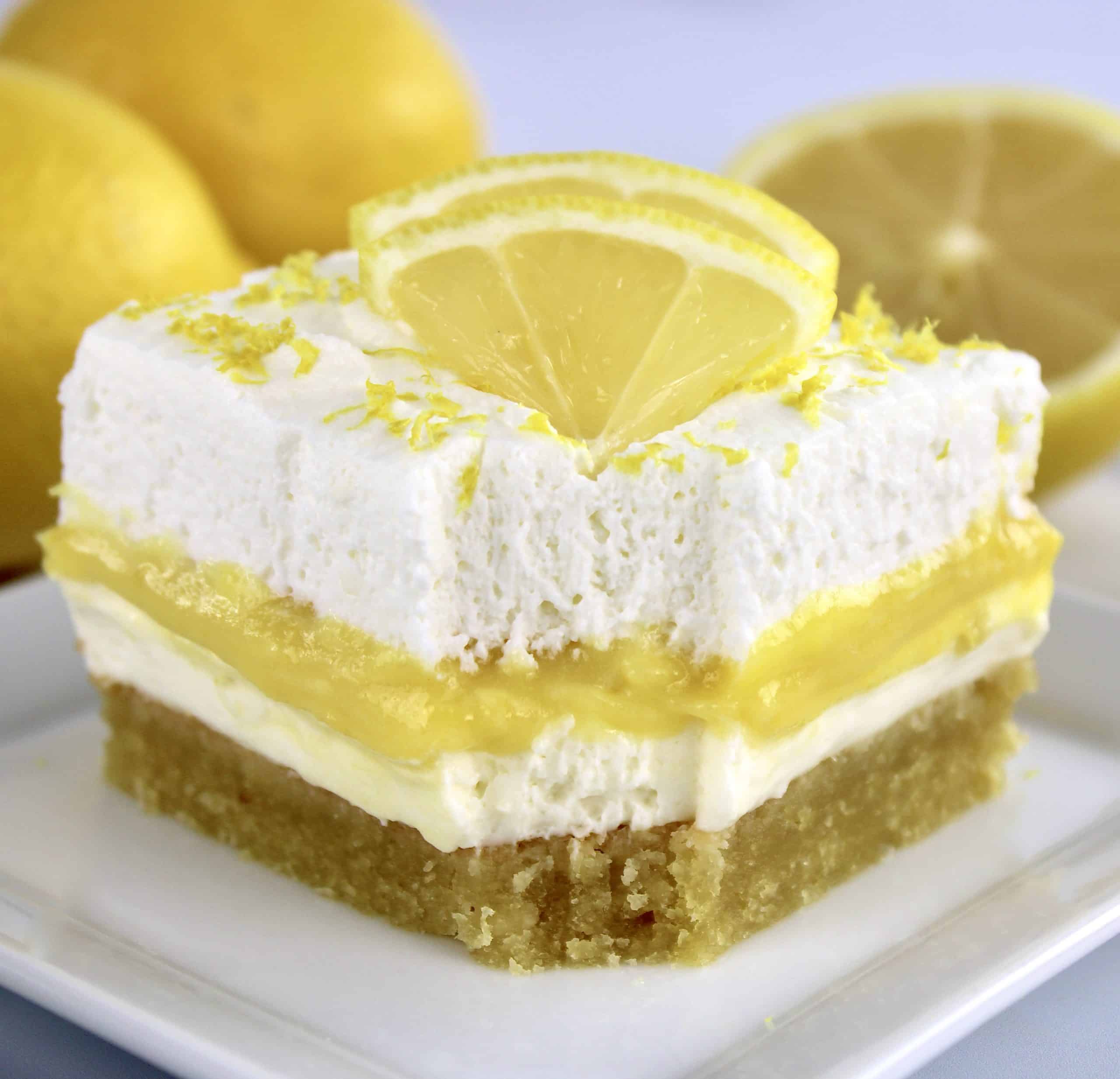 slice of lemon lush with bite missing on white plate with lemon slices on top