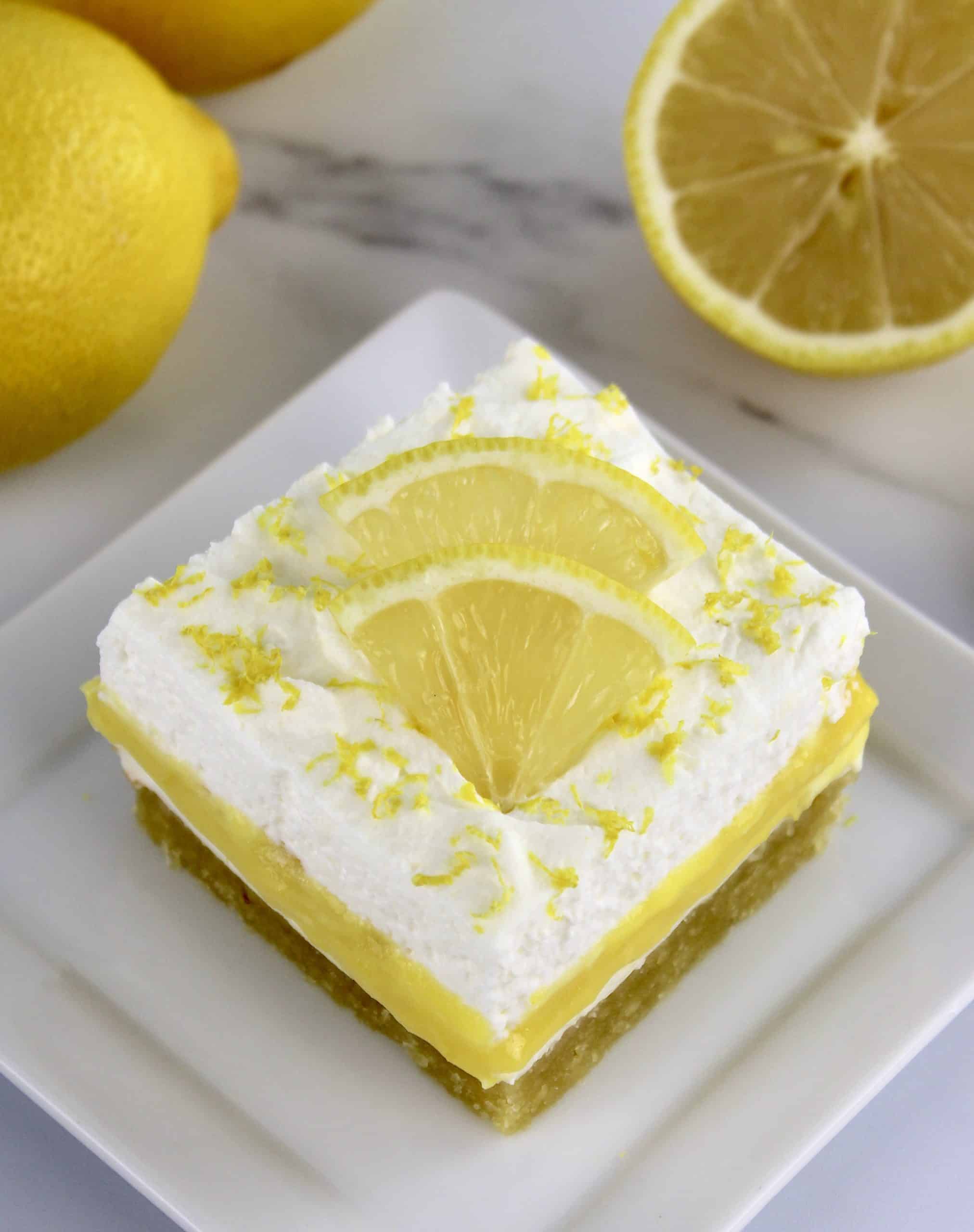 overhead view of Keto Lemon Lush slice on white plate with lemon slices on top