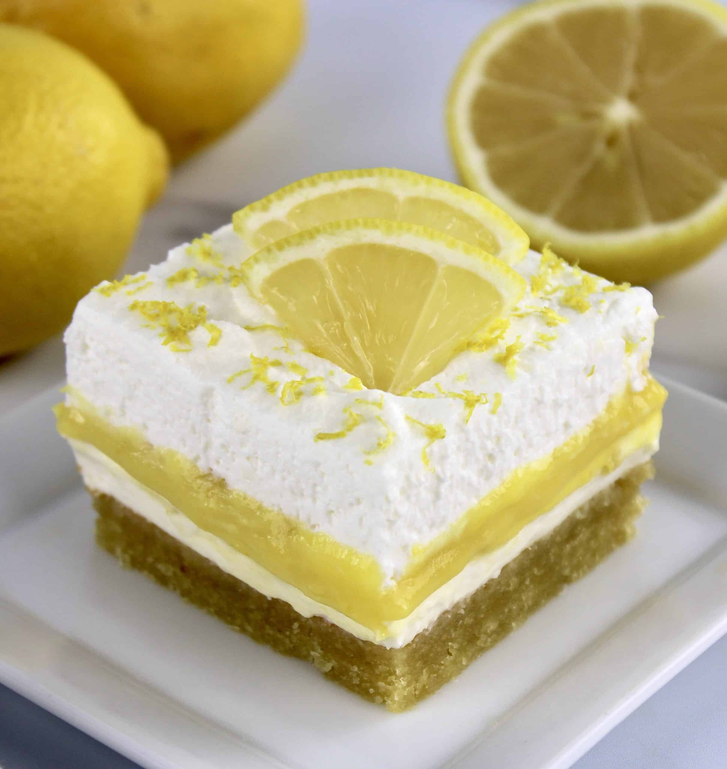 Keto Lemon Lush slice on white plate with slices of lemon on top