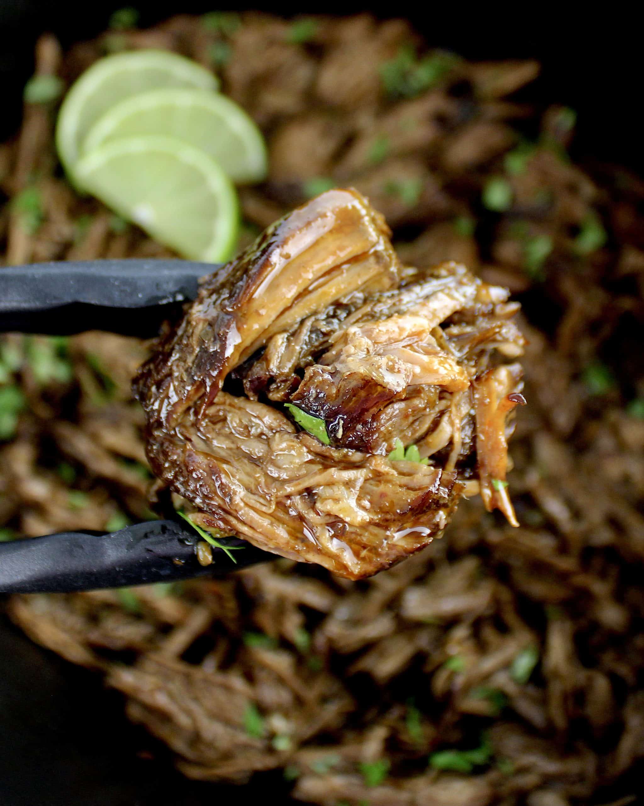 Slow Cooker Beef Barbacoa with tongs holding up some