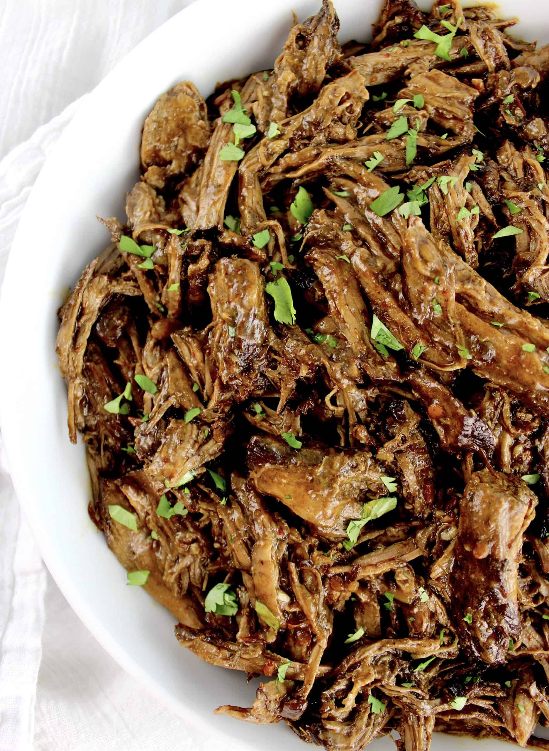 Slow Cooker Beef Barbacoa in white bowl with chopped cilantro