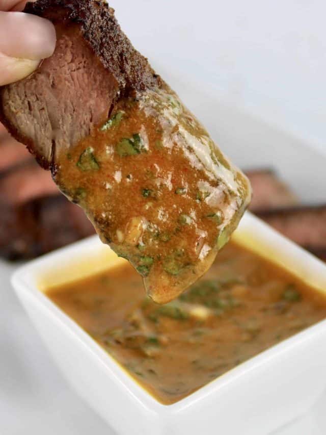 slice of steak dipped into Cowboy Butter in white square bowl