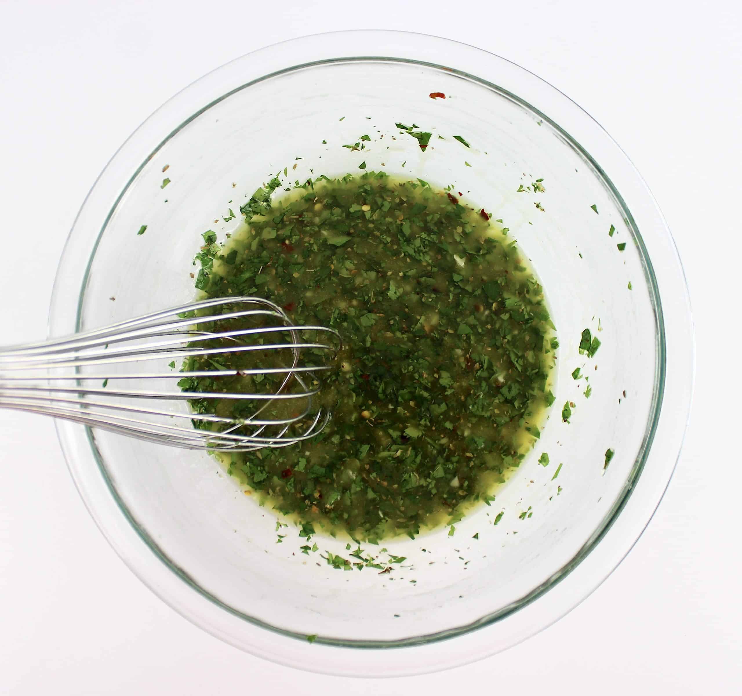 Chimichurri Sauce in glass bowl with whisk