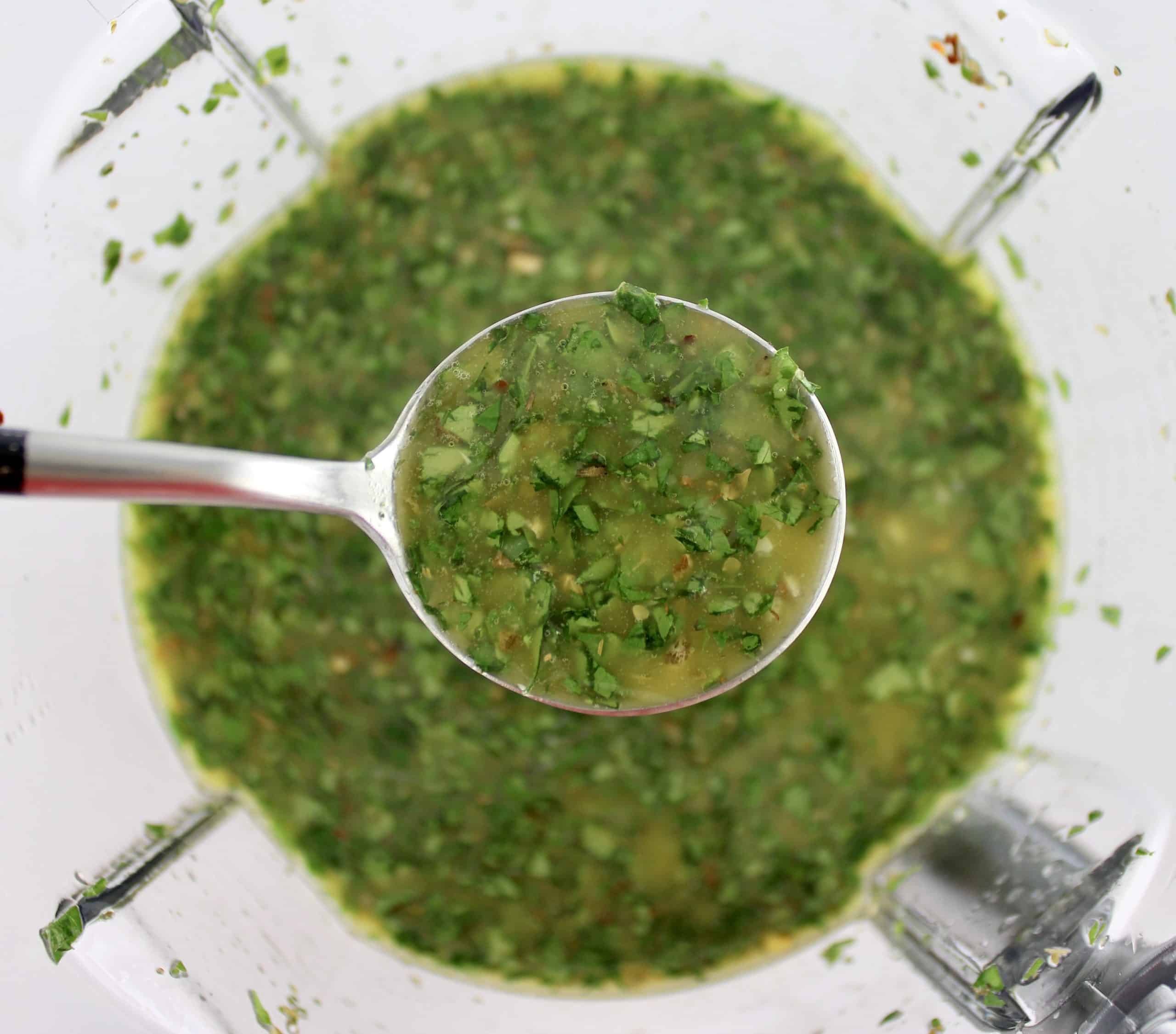 Chimichurri Sauce being spooned out of food processor bowl