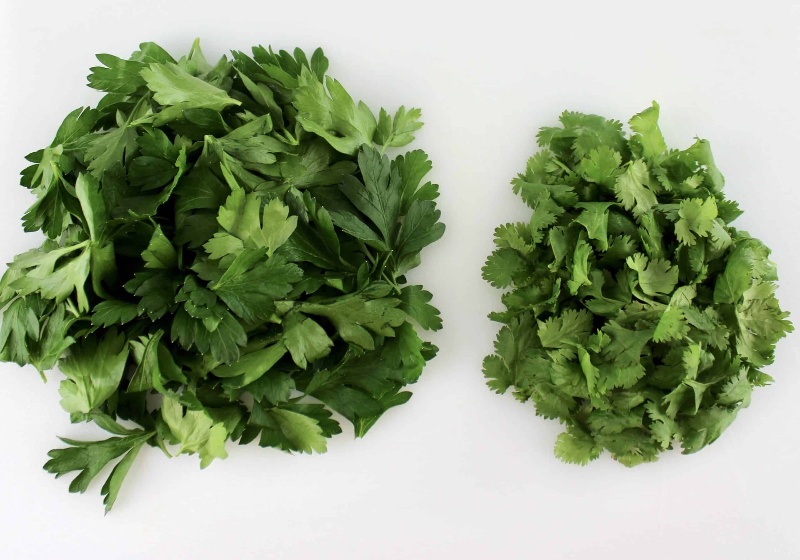 parsley and cilantro leaves on white cutting board