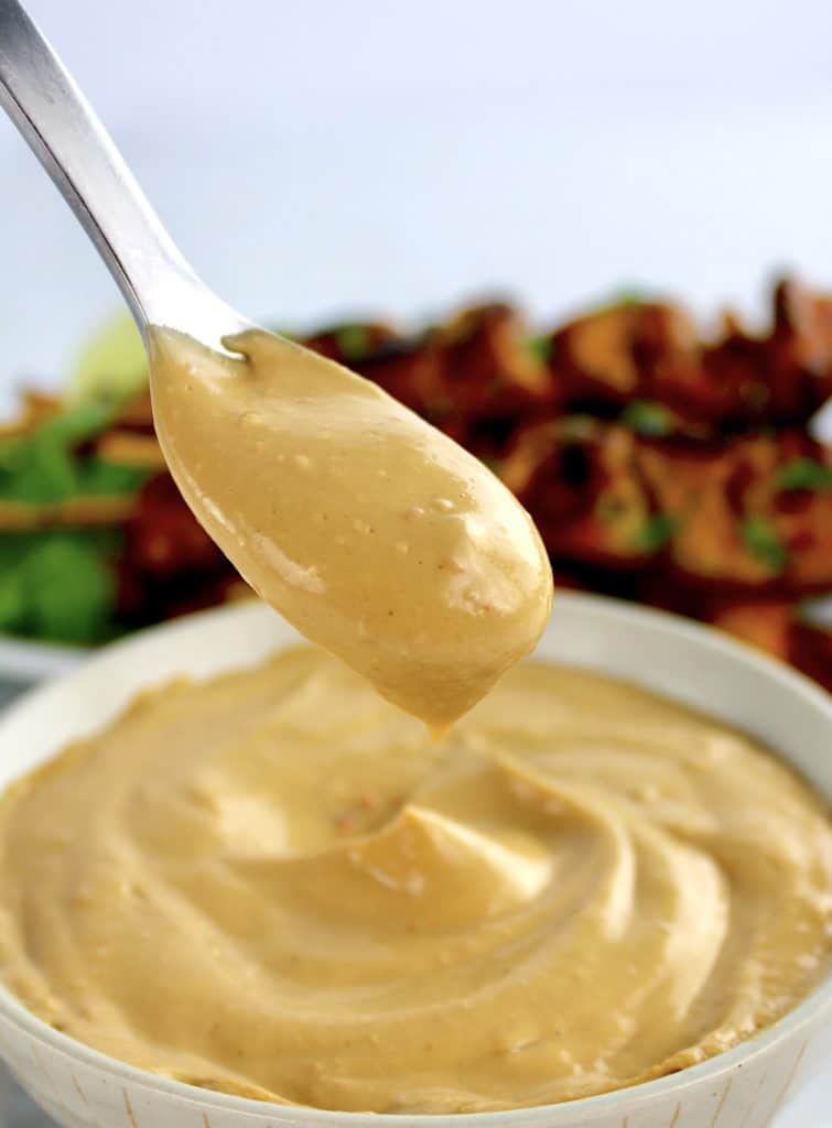 Peanut Sauce in spoon dripping into white bowl