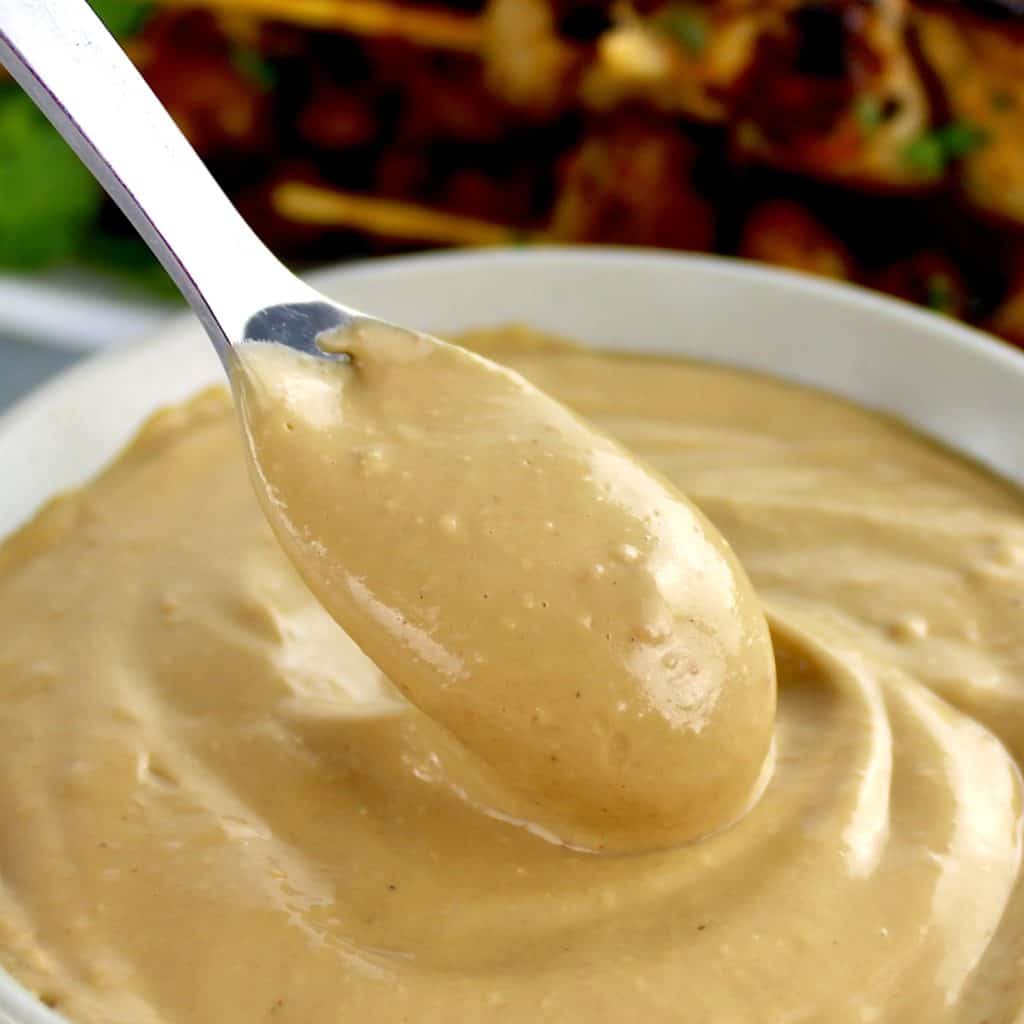 Easy Peanut Sauce in beige bowl with spoon scooping out some
