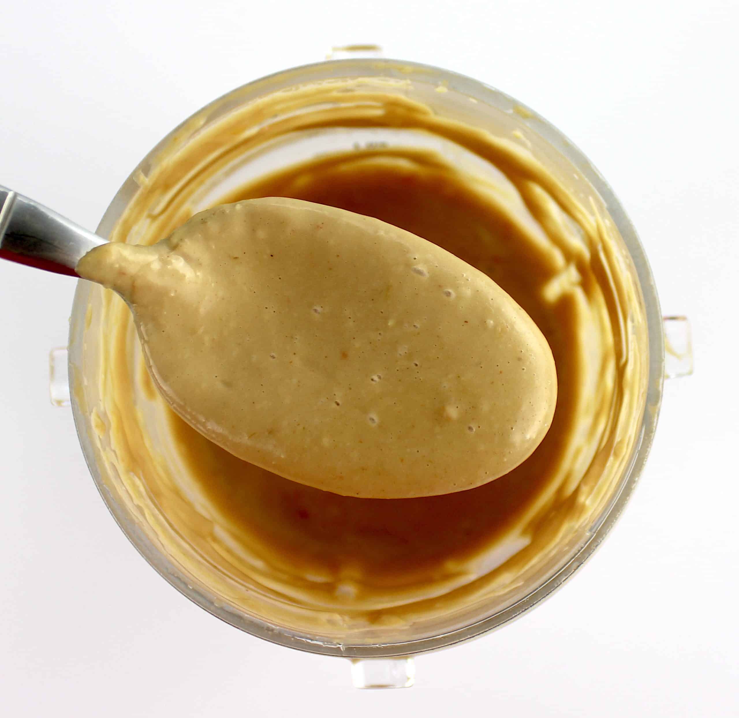 peanut sauce in spoon held up over bullet blender cup