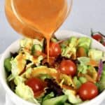 Keto Catalina Dressing being poured over salad in white bowl