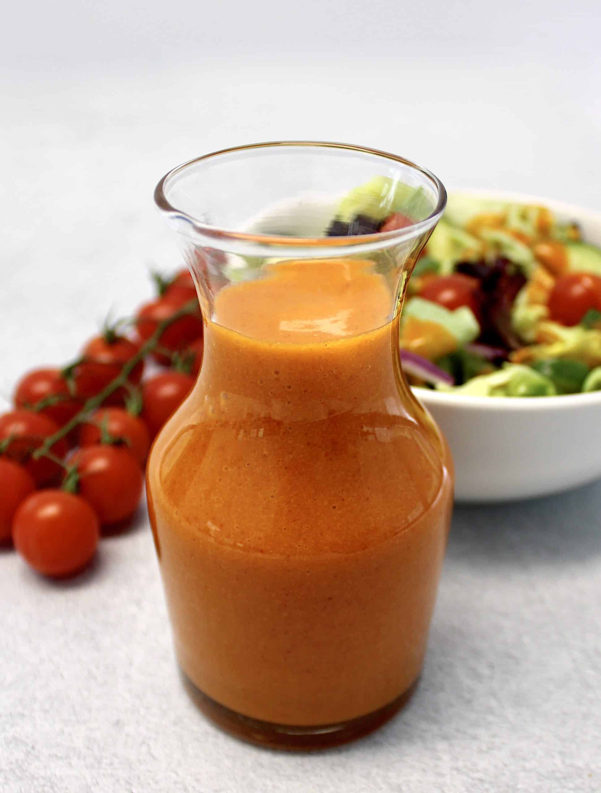 Keto Catalina Dressing in glass jar with salad and tomatoes in background