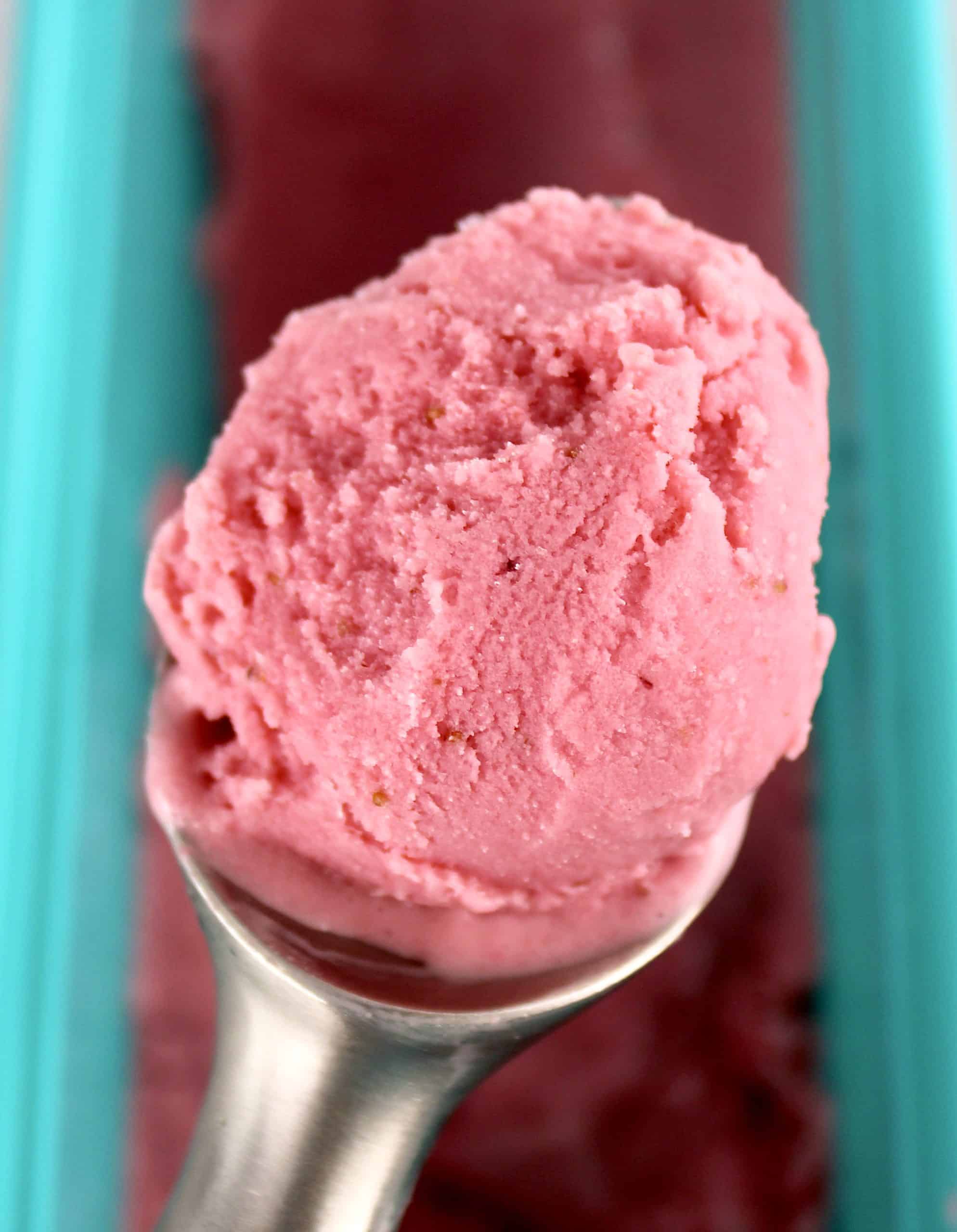 closeup of scoop of Keto Strawberry Frozen Yogurt held over ice cream container