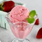 Keto Strawberry Frozen Yogurt in glass with pint of strawberries in background