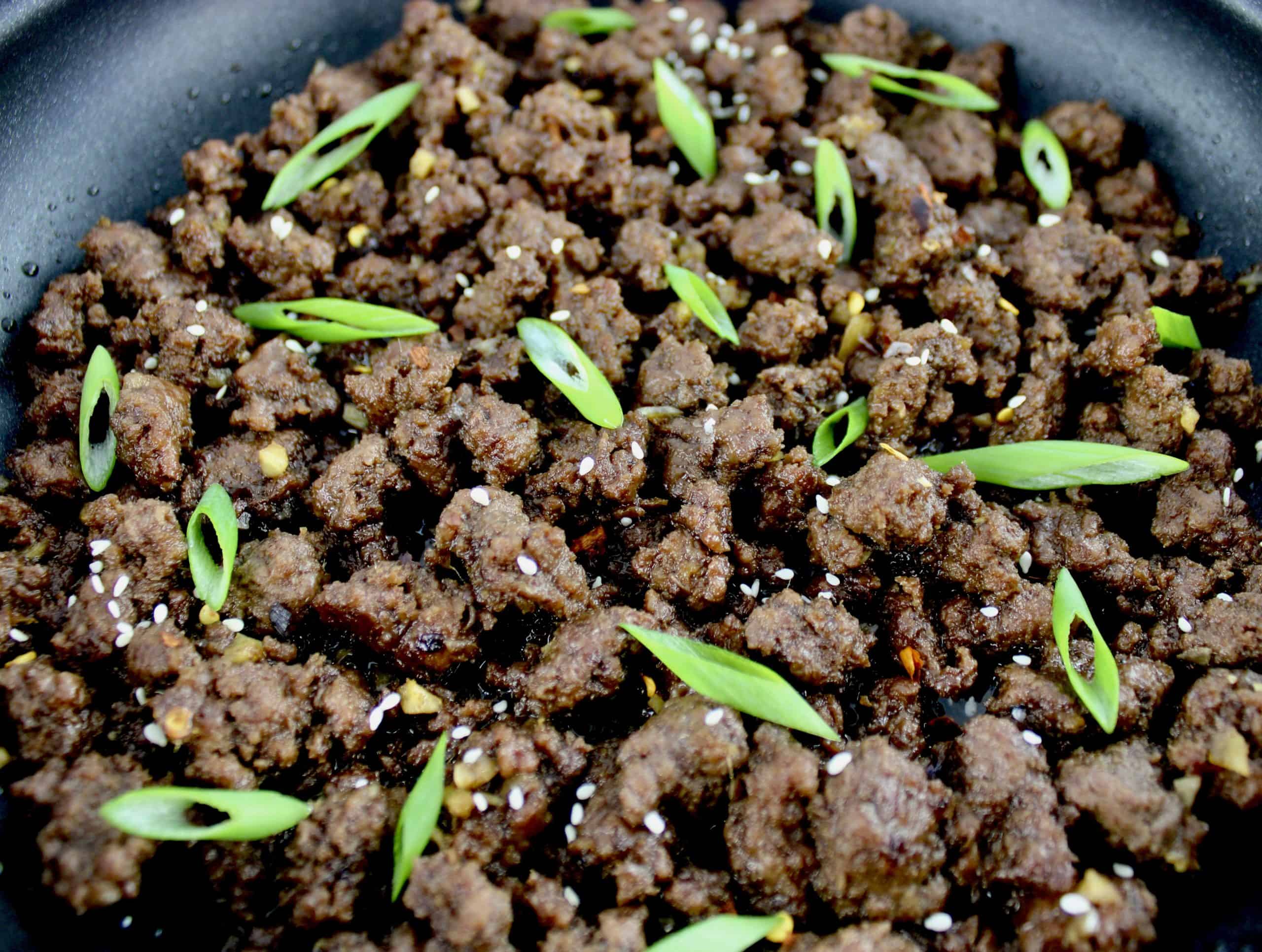 Korean Beef in skillet with sliced scallions