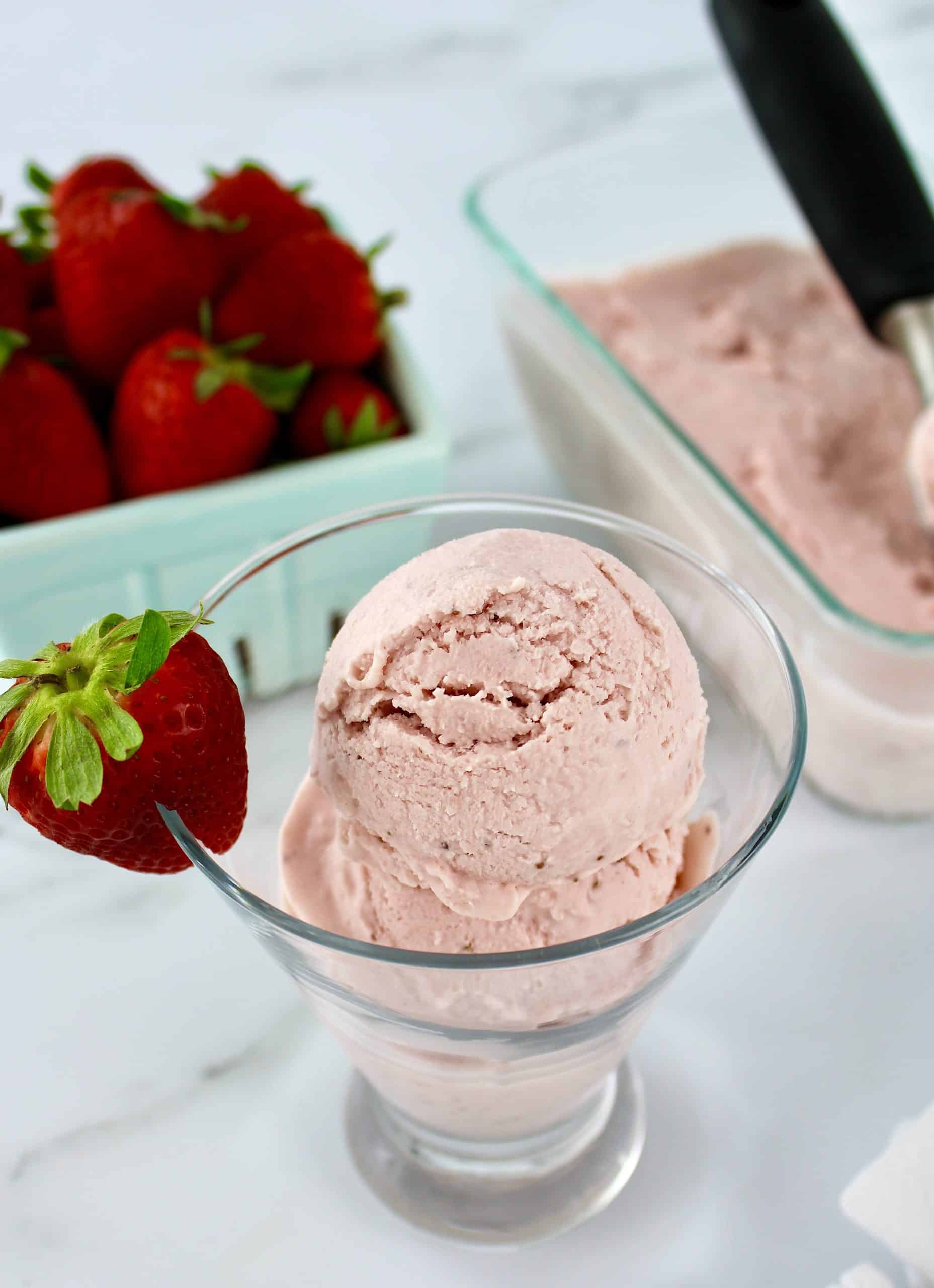 No Churn Keto Strawberry Ice Cream in glass dish with strawberries in background