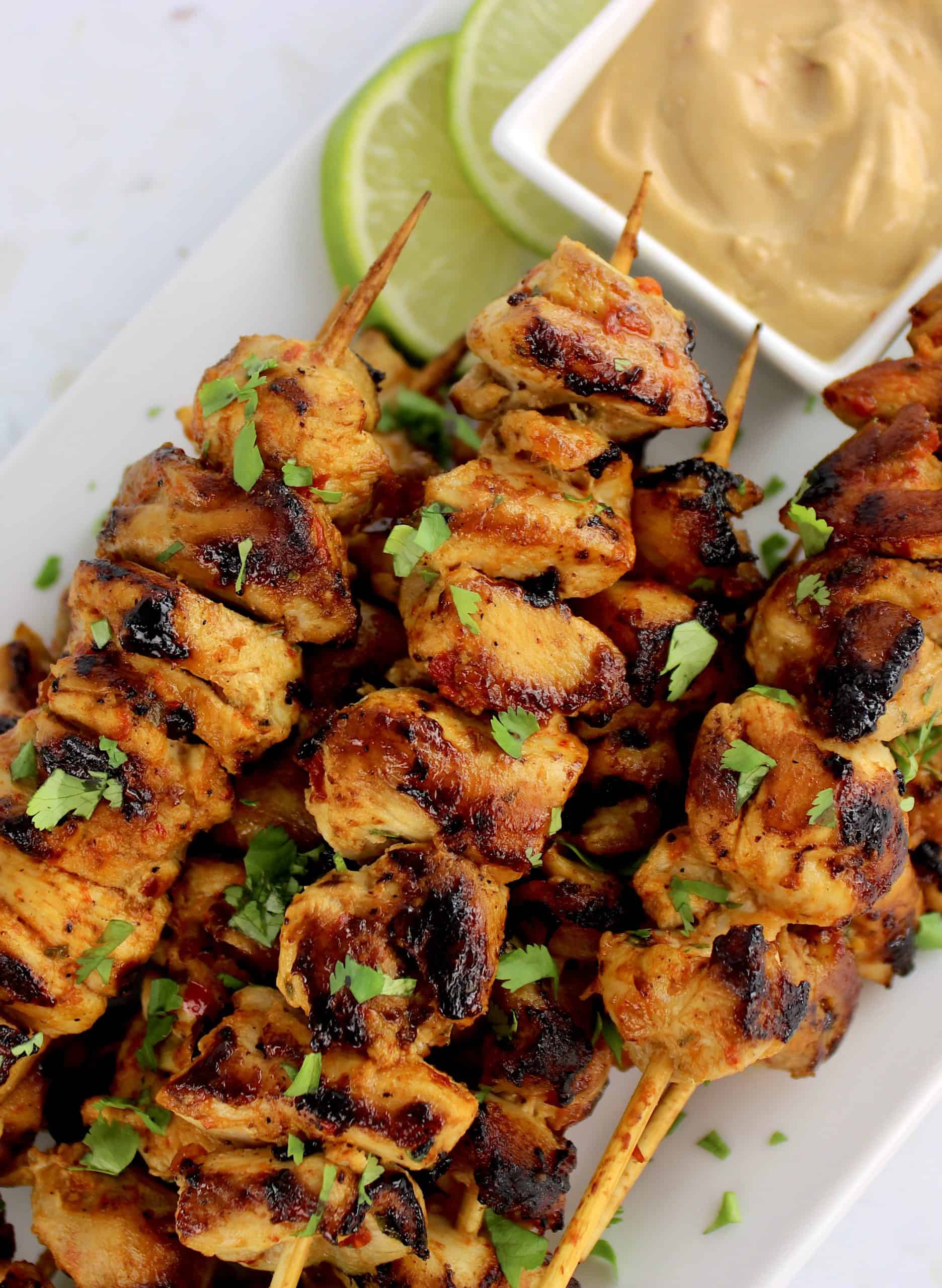 Thai Chicken Satay skewers on white plate with peanut sauce on side