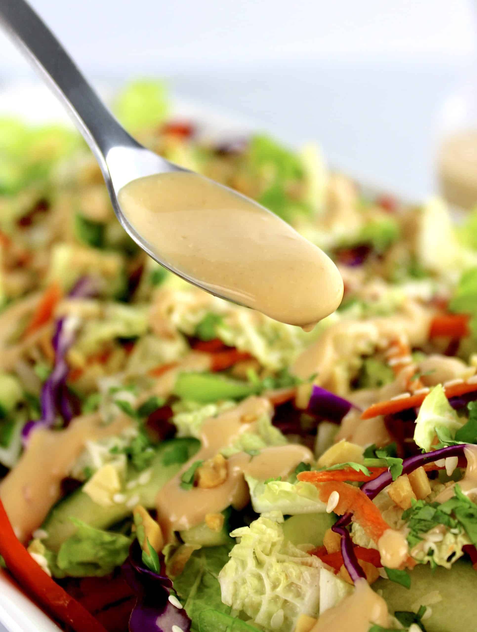 peanut dressing being spooned over thai crunch salad