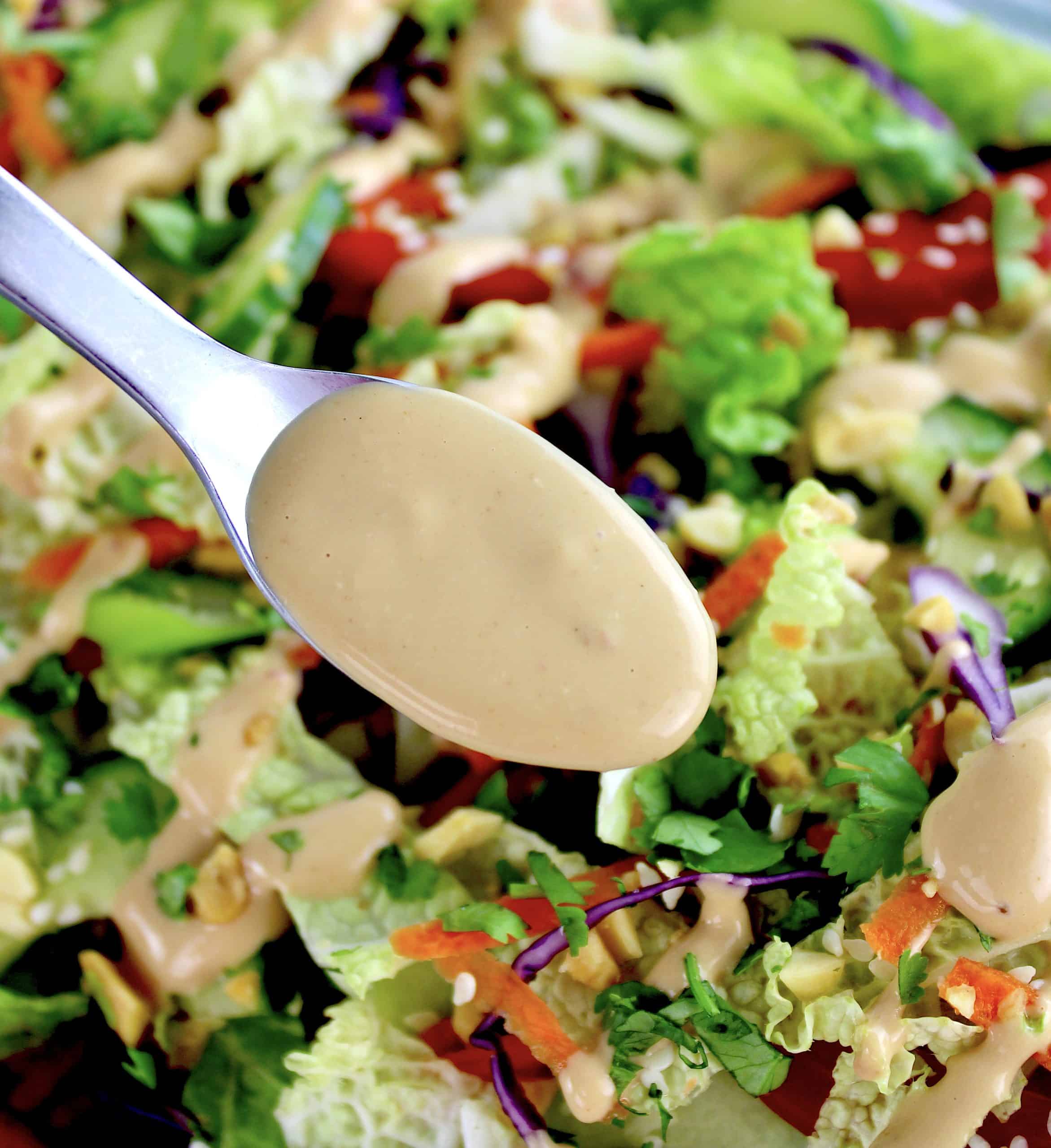 peanut dressing being spooned over thai crunch salad