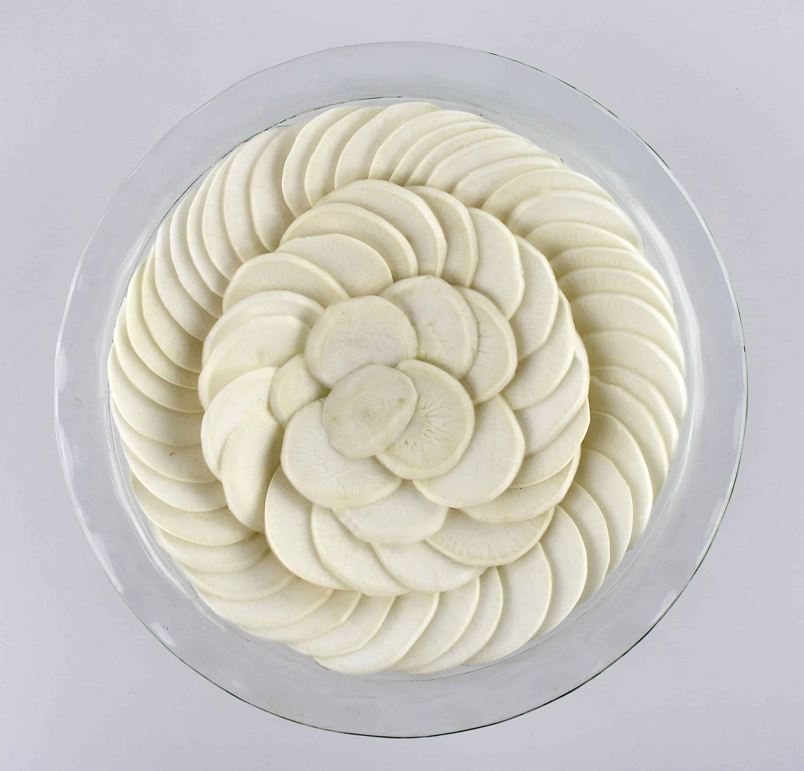 turnips slices arranged in concentric circles in glass pie dish