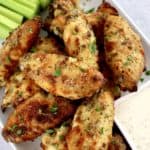 Baked Ranch Chicken Wings on white plate with celery sticks and ranch dressing in white square bowl