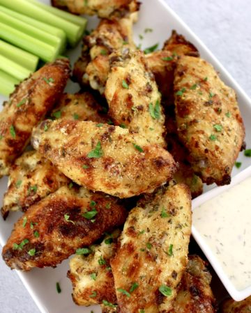 Baked Ranch Chicken Wings on white plate with celery sticks and ranch dressing in white square bowl