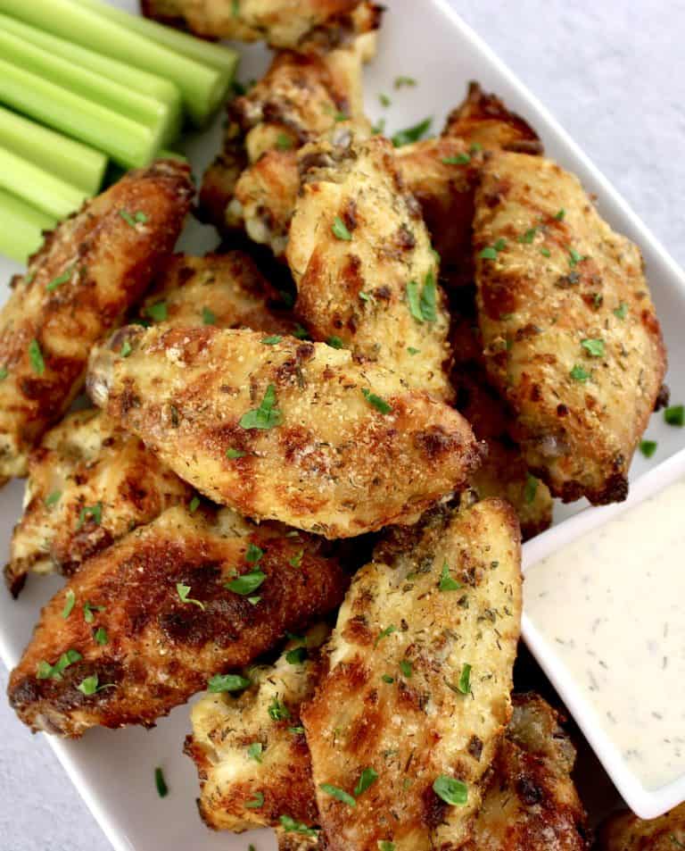 Baked Ranch Chicken Wings on white plate with celery sticks and ranch dressing in white square bowl