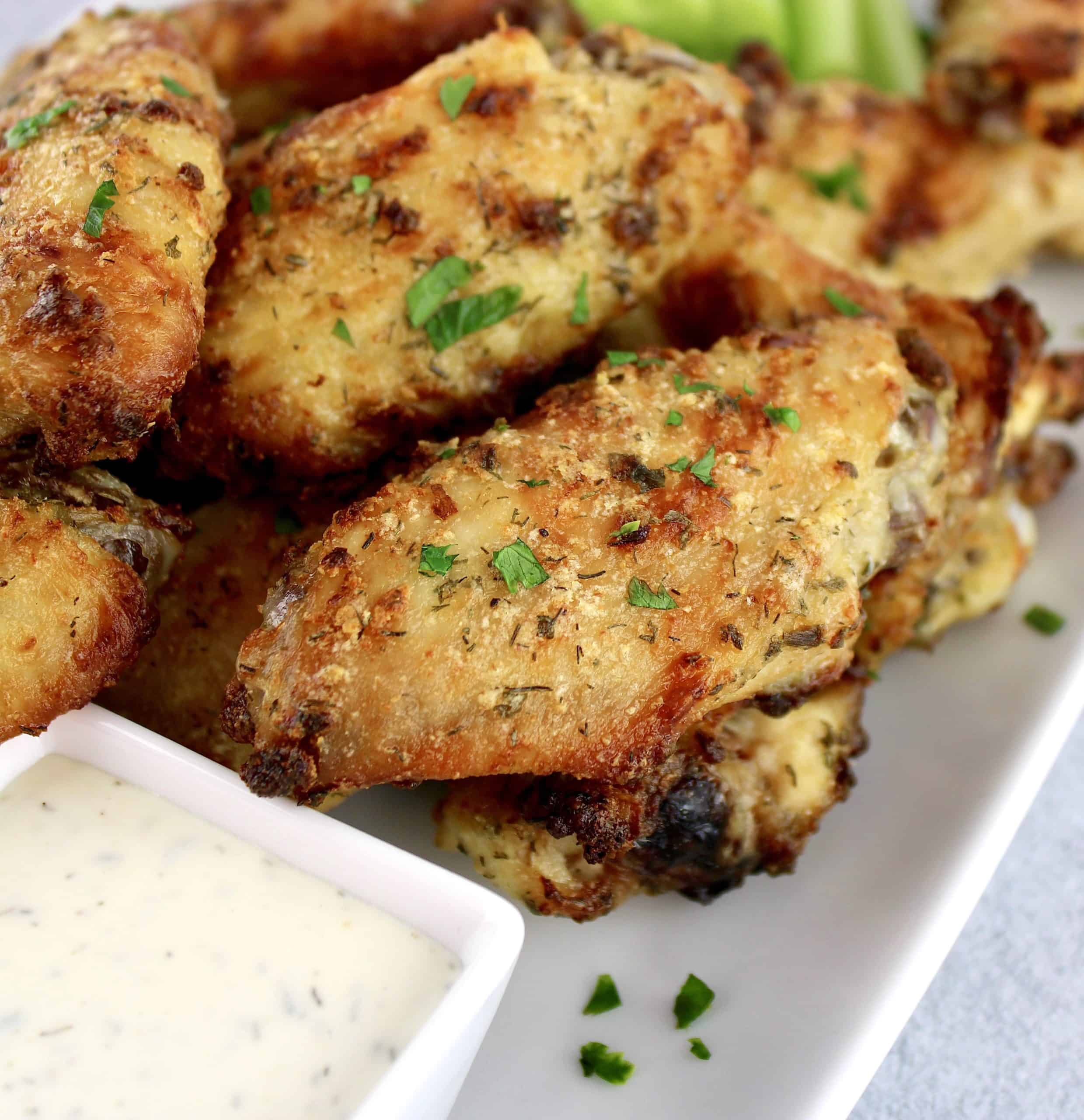 closeup of ranch chicken wings on platter with ranch dip and celery sticks on side