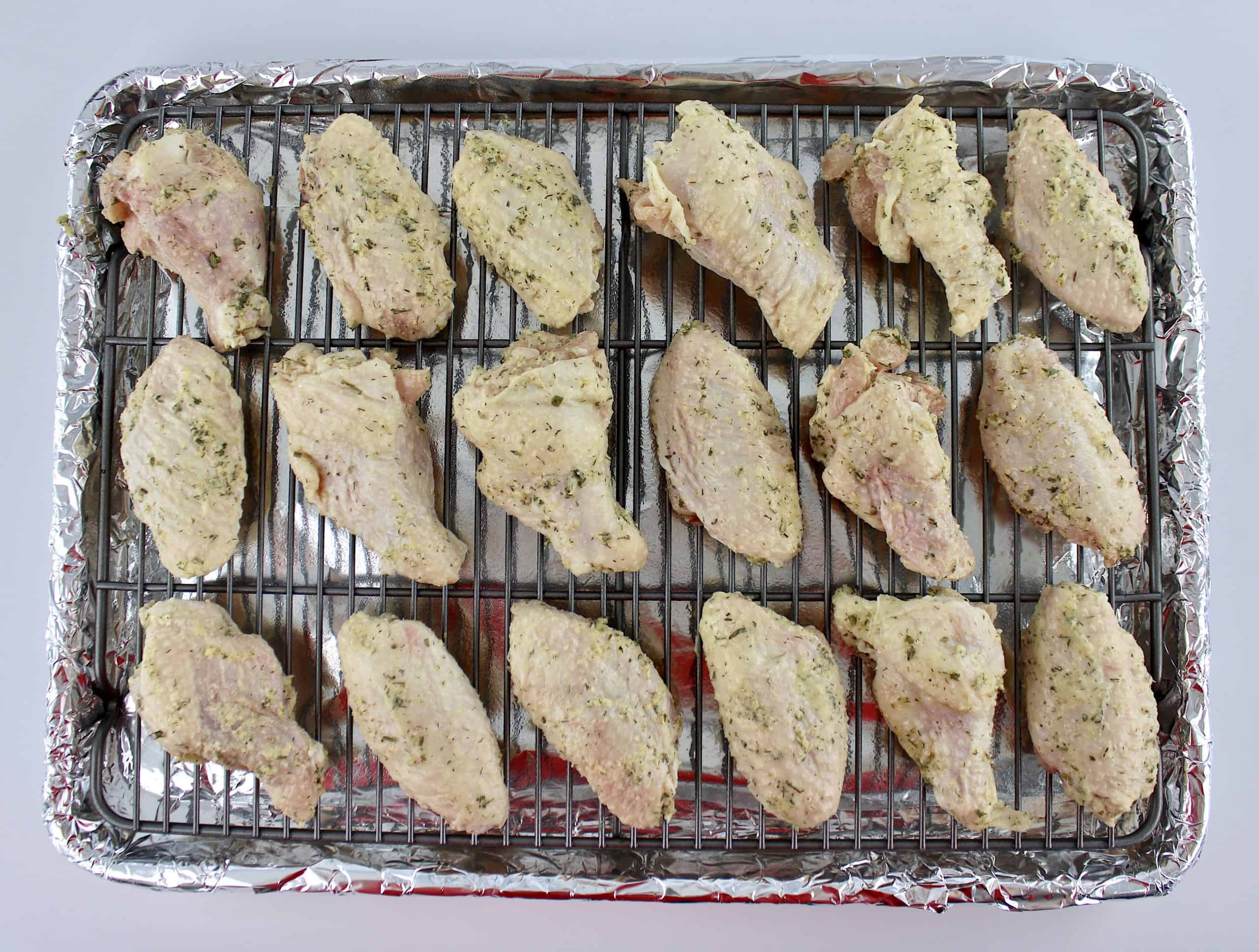 raw seasoned chicken wings on baking sheet with wire rack