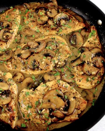 chicken marsala with sliced mushrooms in skillet with chopped parsley