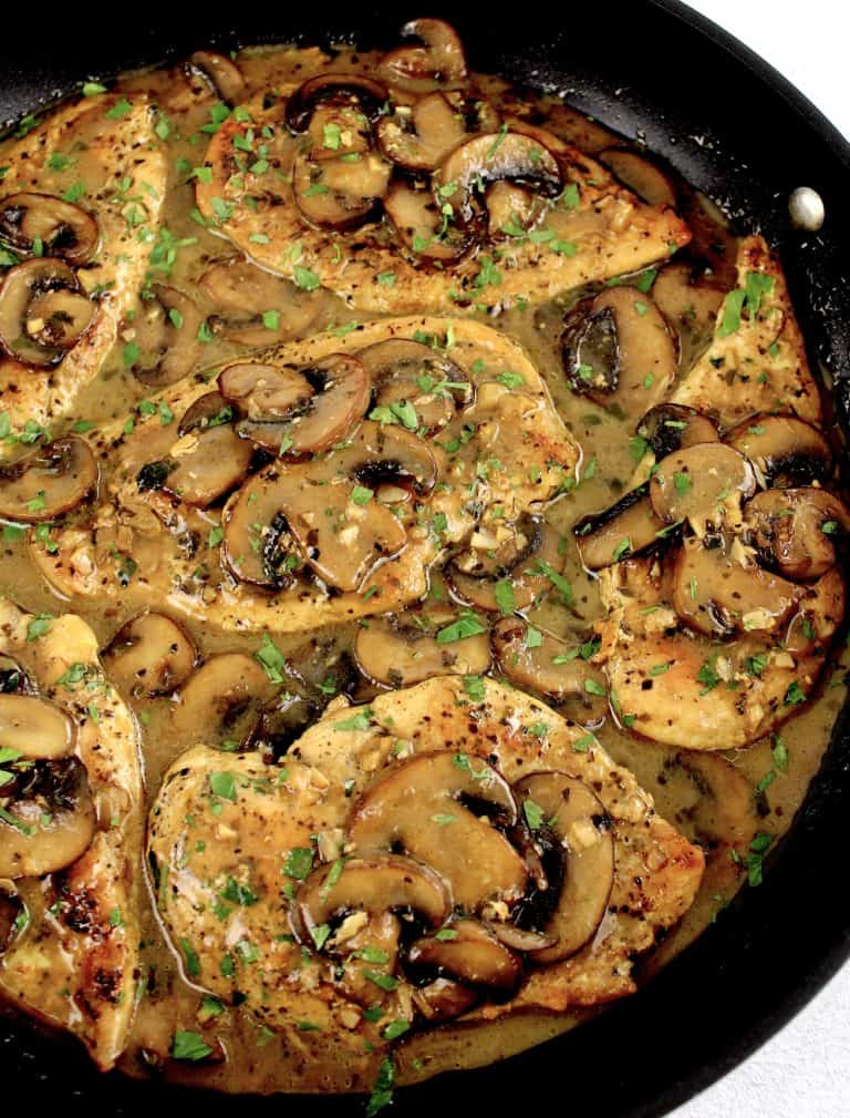 chicken marsala with sliced mushrooms in skillet with chopped parsley